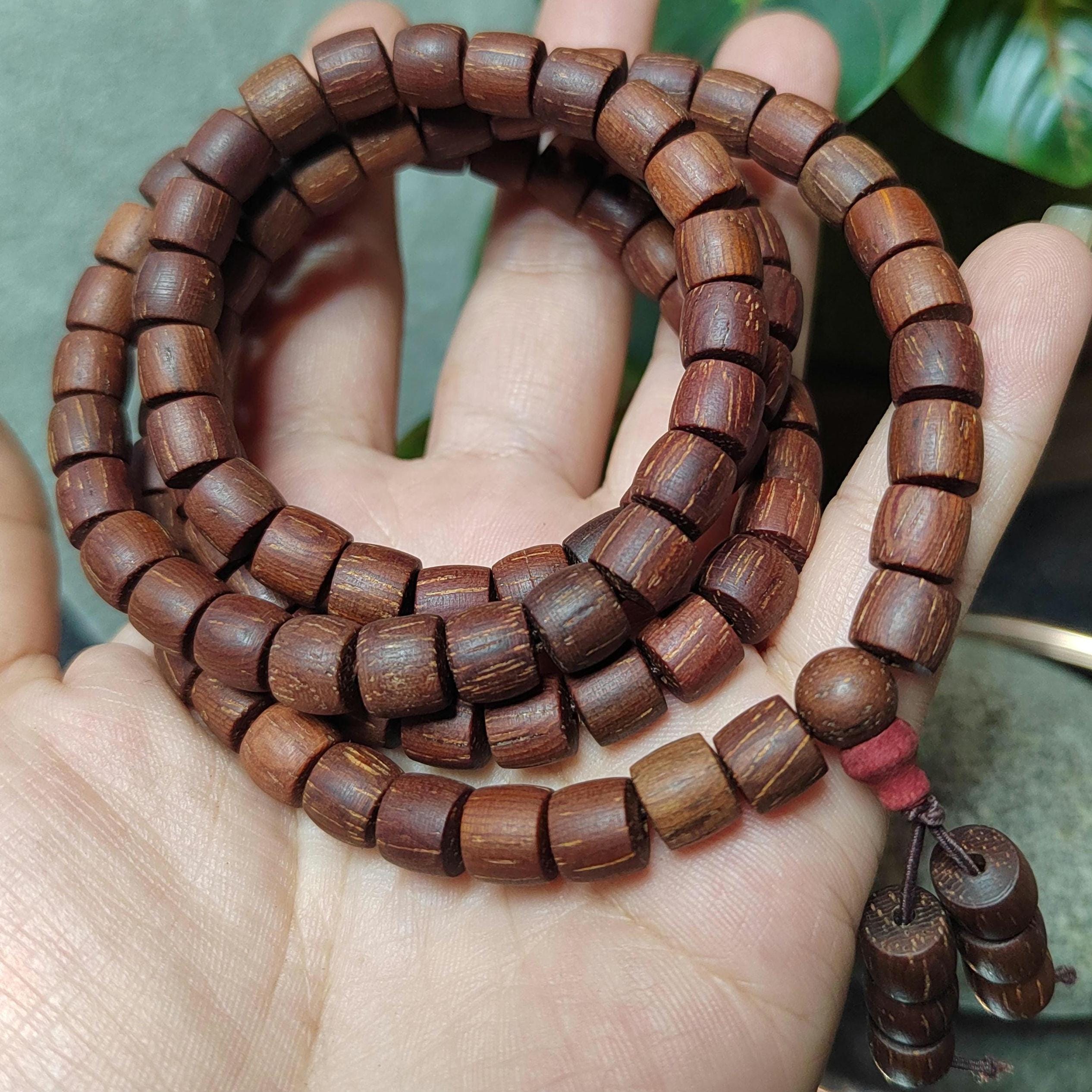 Wooden beaded bracelet on a hand with a blurred green background