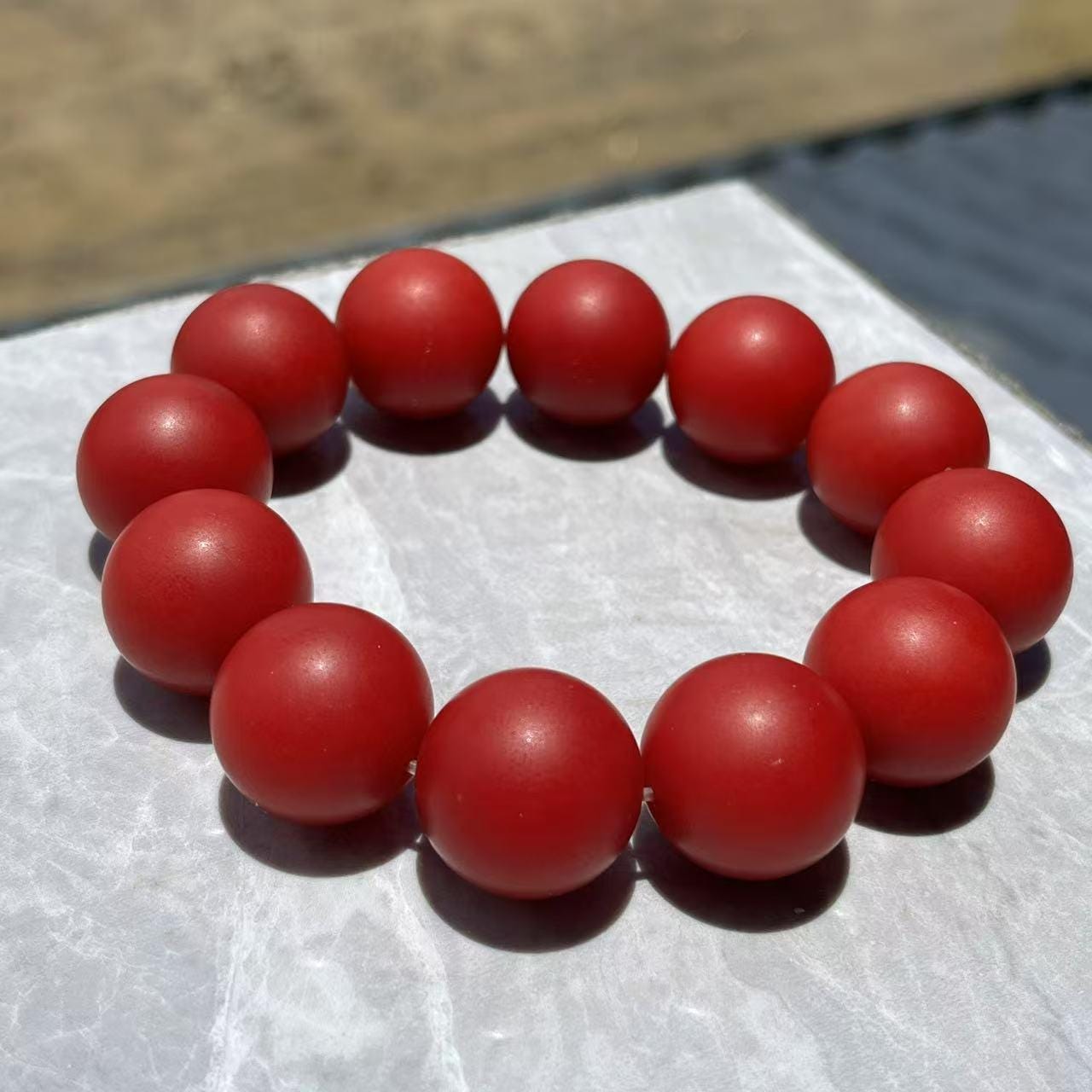 Red beaded bracelet on a white surface with a blurred background