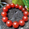 Red beaded bracelet on a textured surface with a natural background