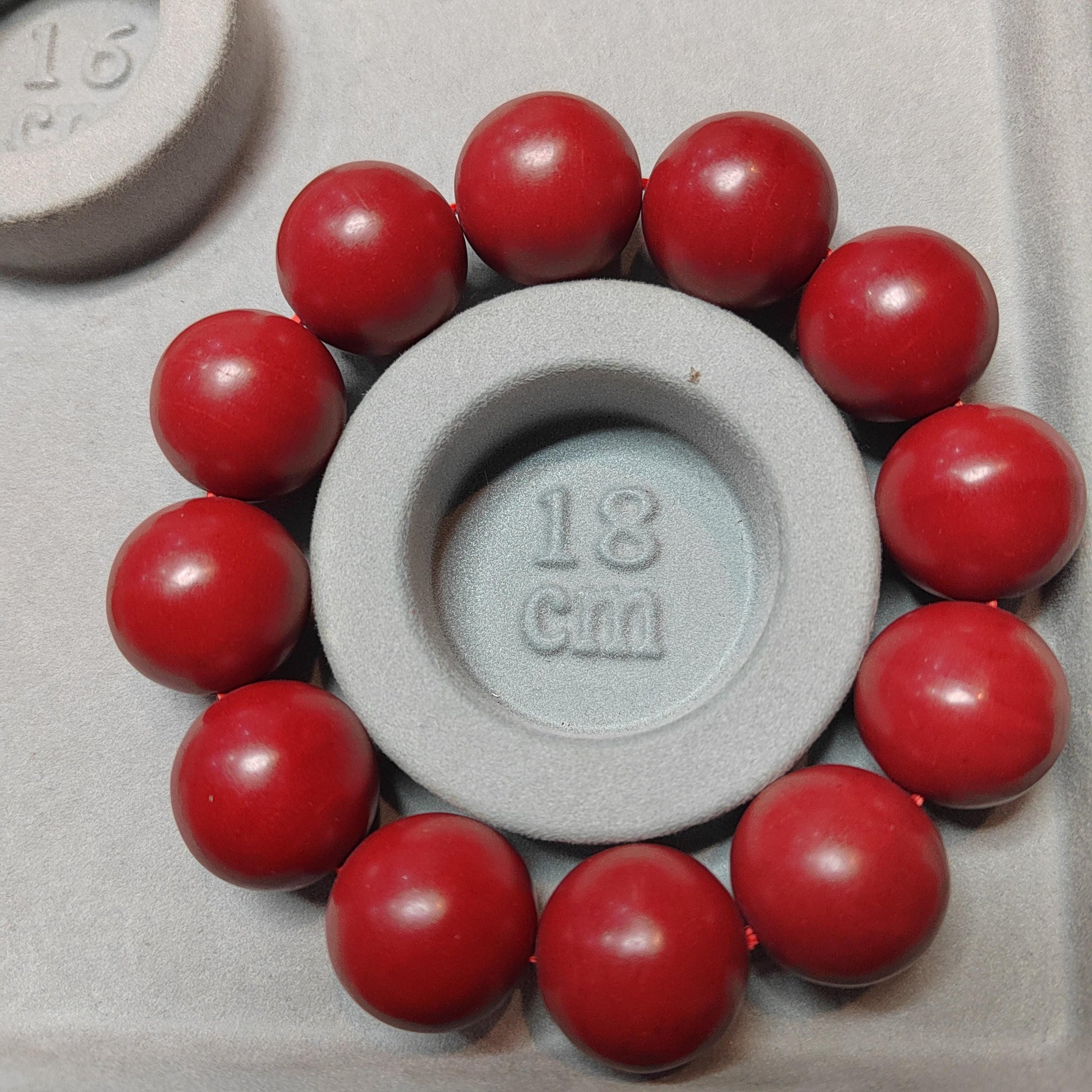 Red spherical objects surrounding a circular object with '18 cm' marking on a gray background