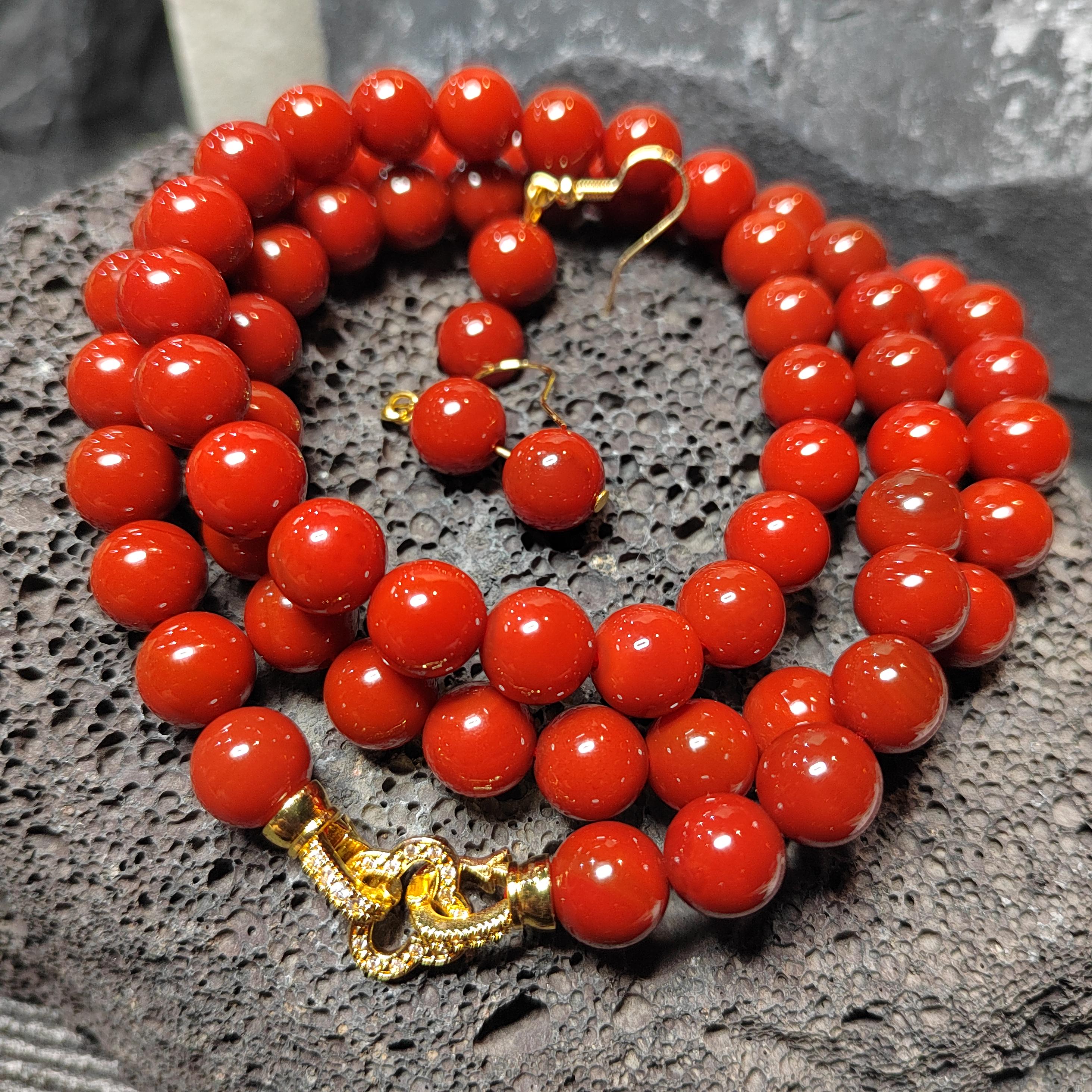 Red beaded bracelet with gold clasp on a textured surface