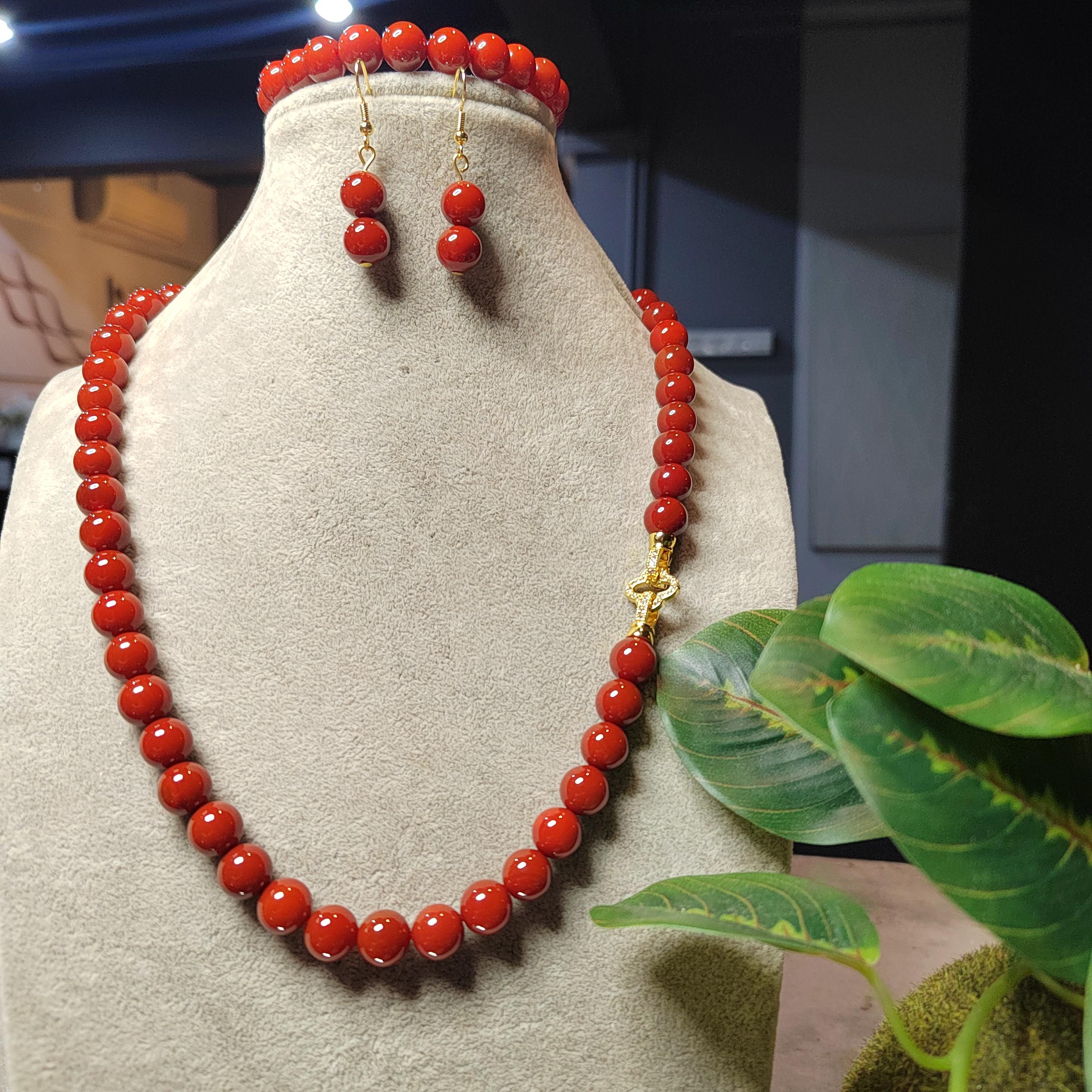 Red beaded necklace and earrings on a mannequin bust with a blurred background