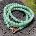 Green beaded bracelet with a rose gold clasp on a textured surface