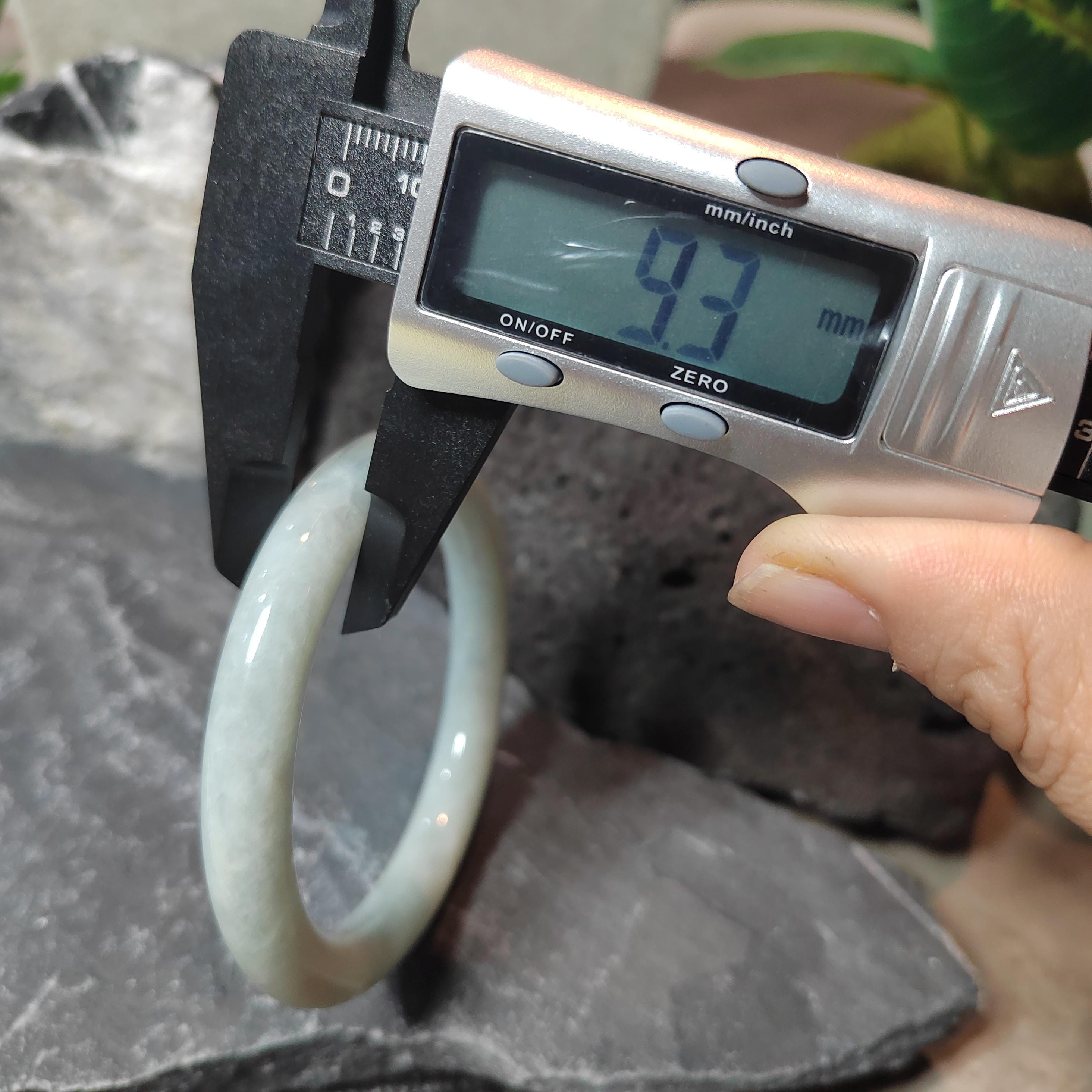 Digital caliper measuring a white ring on a dark surface