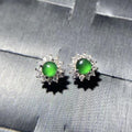 Pair of earrings with green gemstones on a gray fabric background