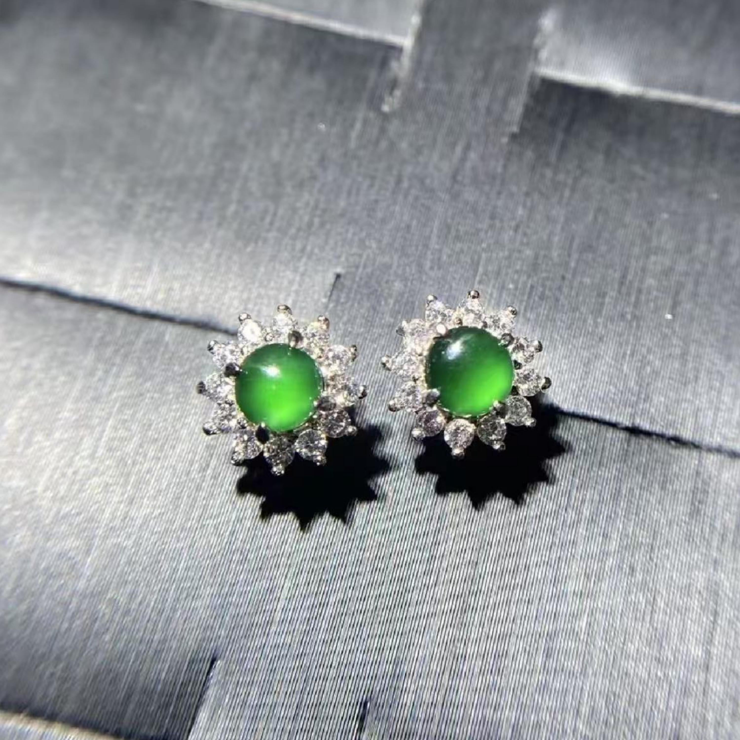 Pair of earrings with green gemstones on a gray fabric background