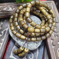 Brown beaded bracelet on a stone surface with intricate background
