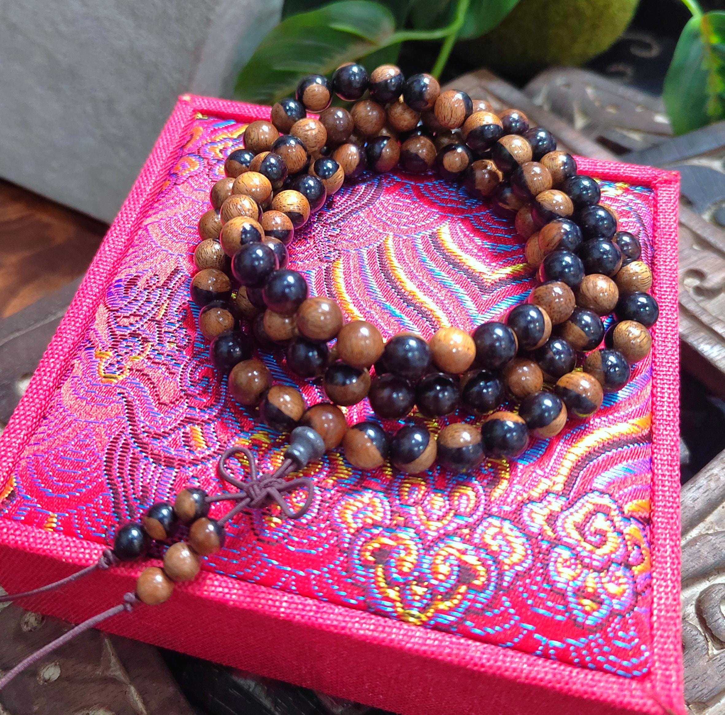 Wooden beaded necklace on a pink embroidered box with green leaves in the background