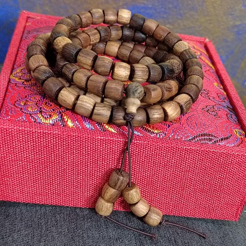 Wooden beaded bracelet on a pink fabric box with a textured background
