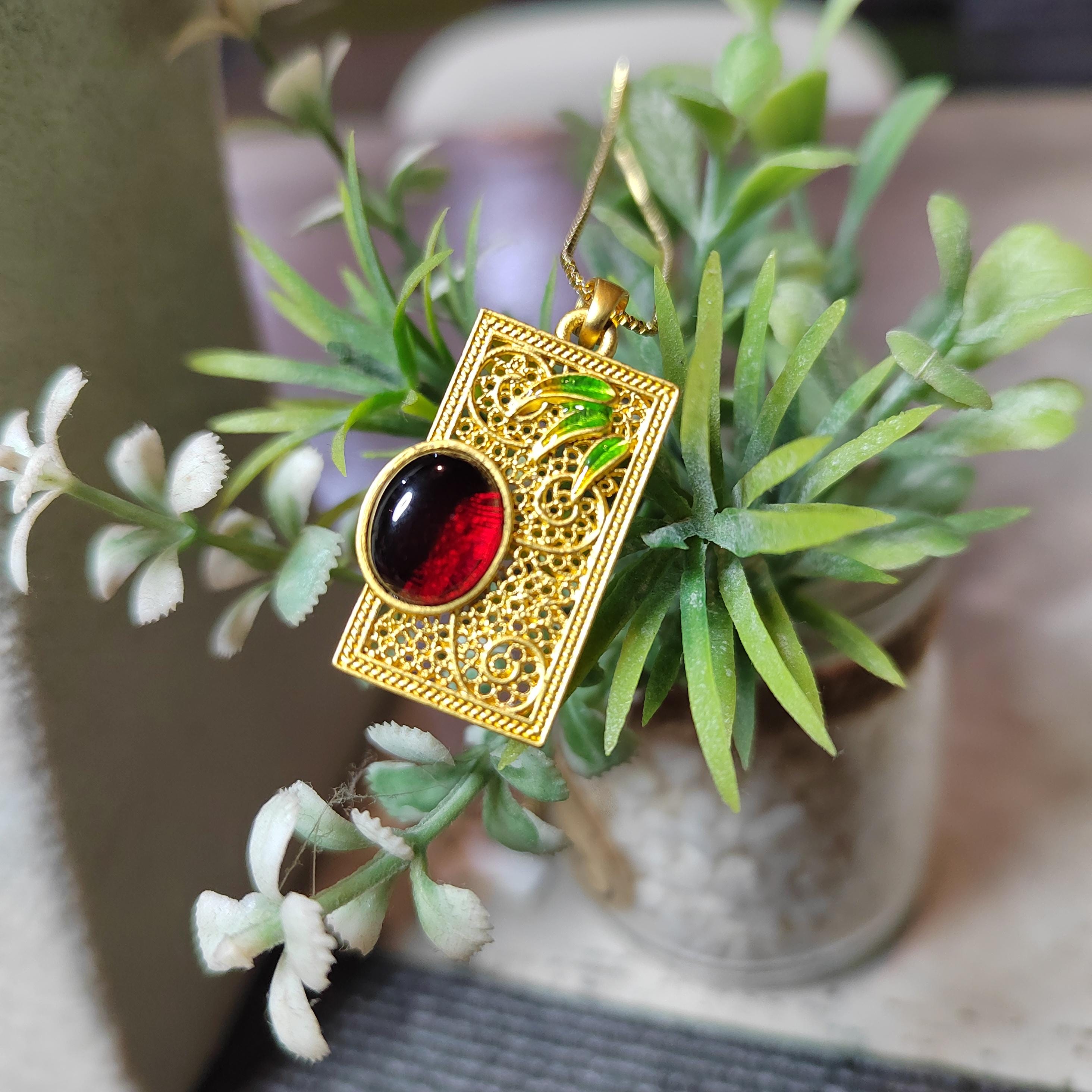Gold pendant with a red amber on a plant background