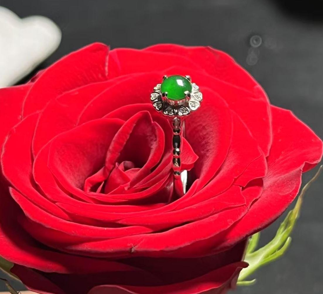 Ring with a green gemstone on a red rose