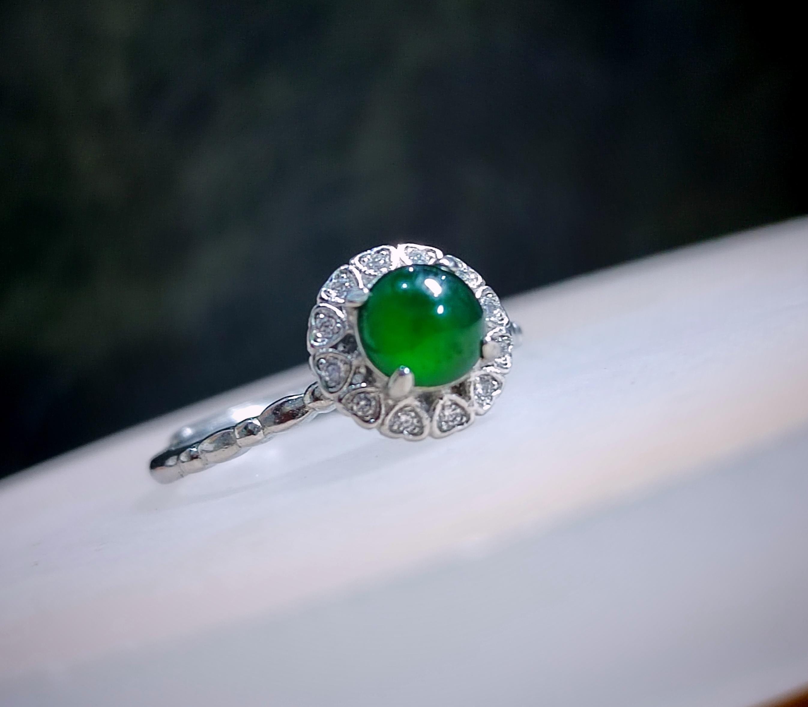 Silver ring with a green gemstone on a dark background