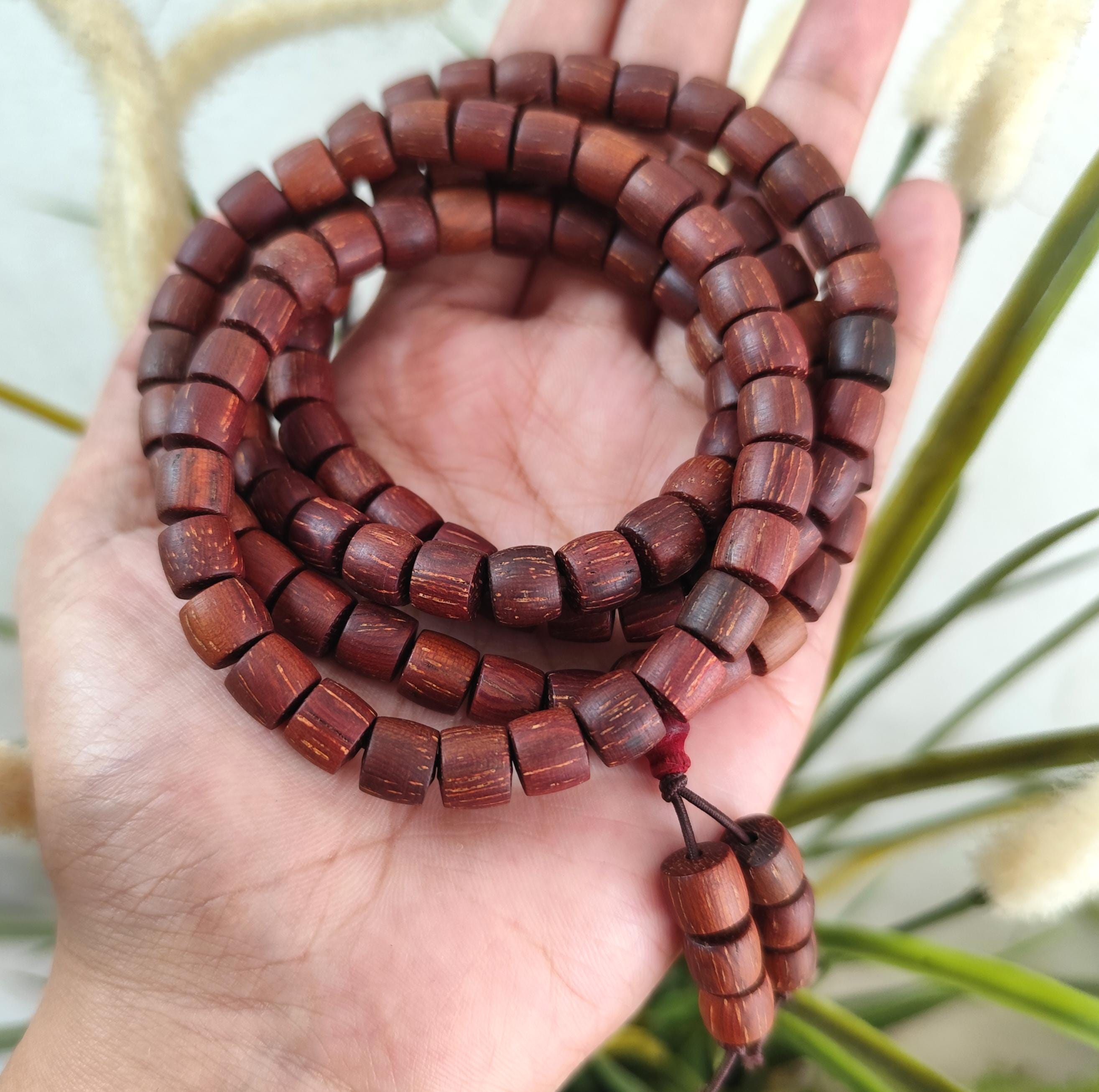 Wooden beaded necklace held in a hand with a natural background