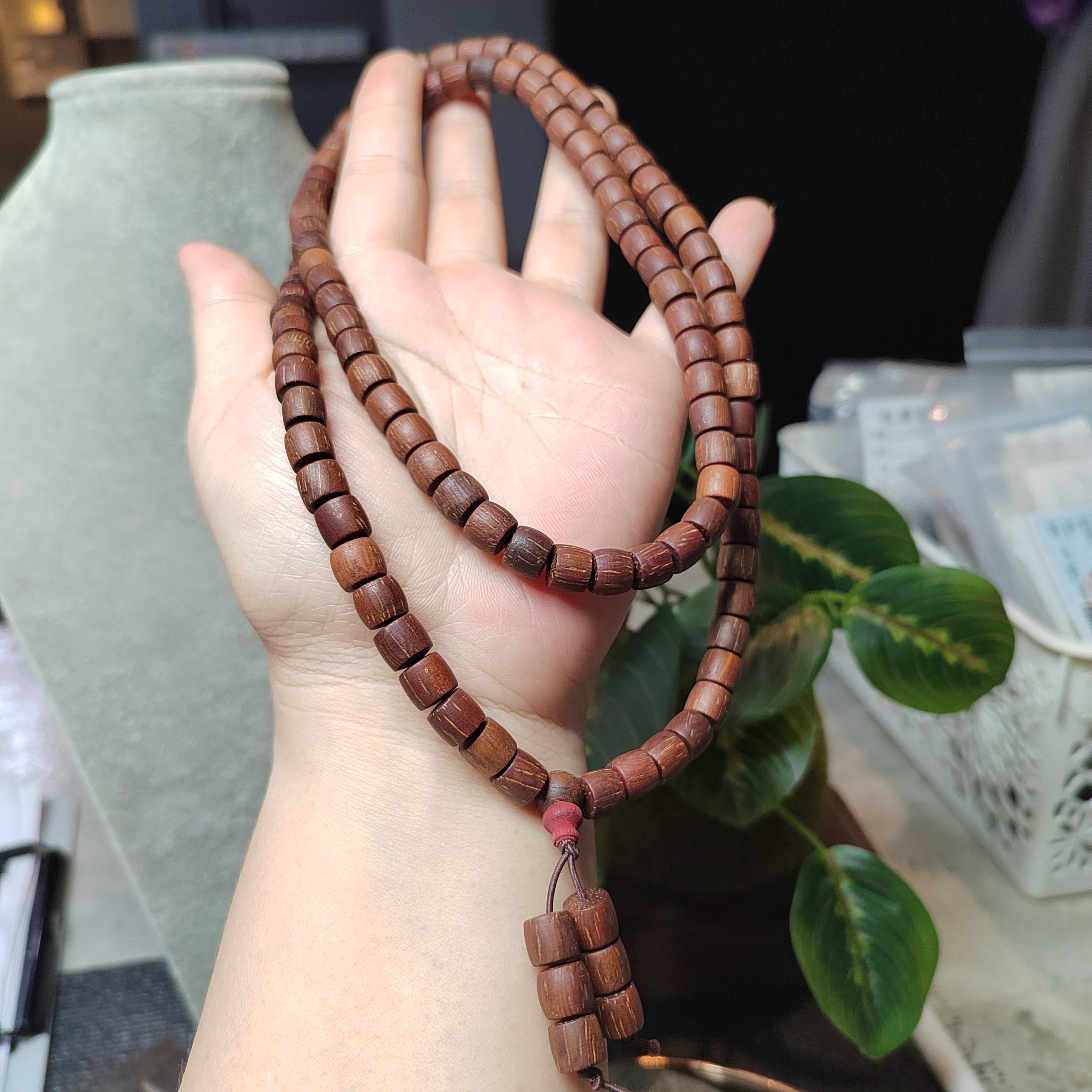 Wooden prayer beads held in a hand with a blurred indoor background