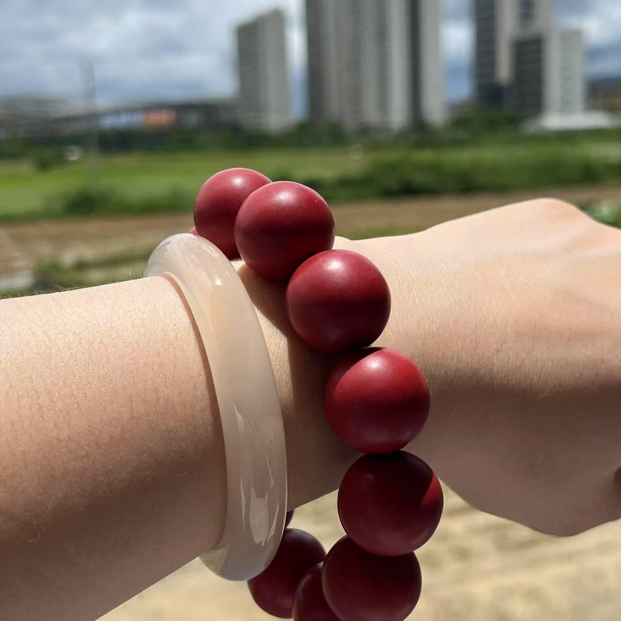 Red beaded bracelet on a wrist with a blurred outdoor background