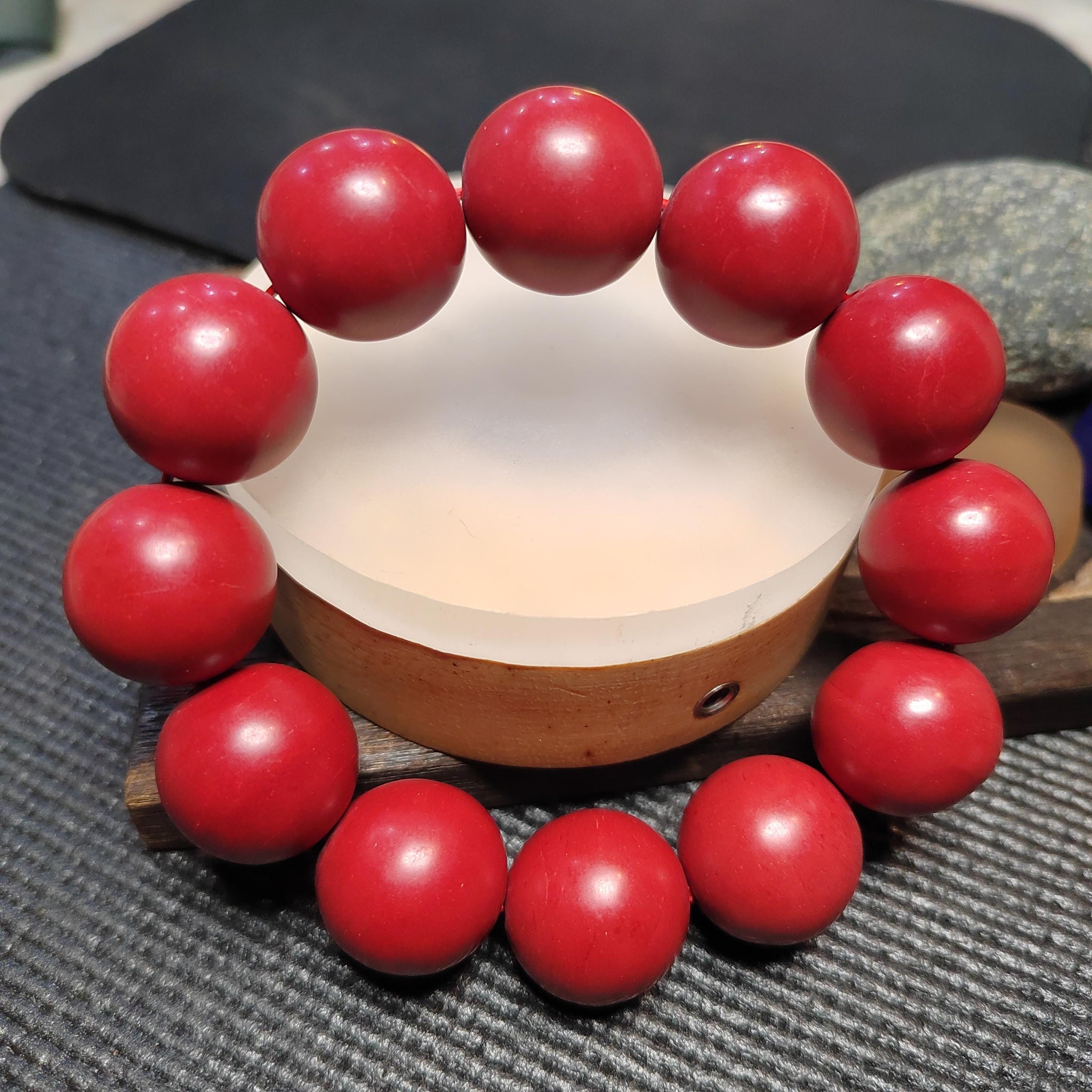 Red beaded bracelet on a wooden base with a blurred background