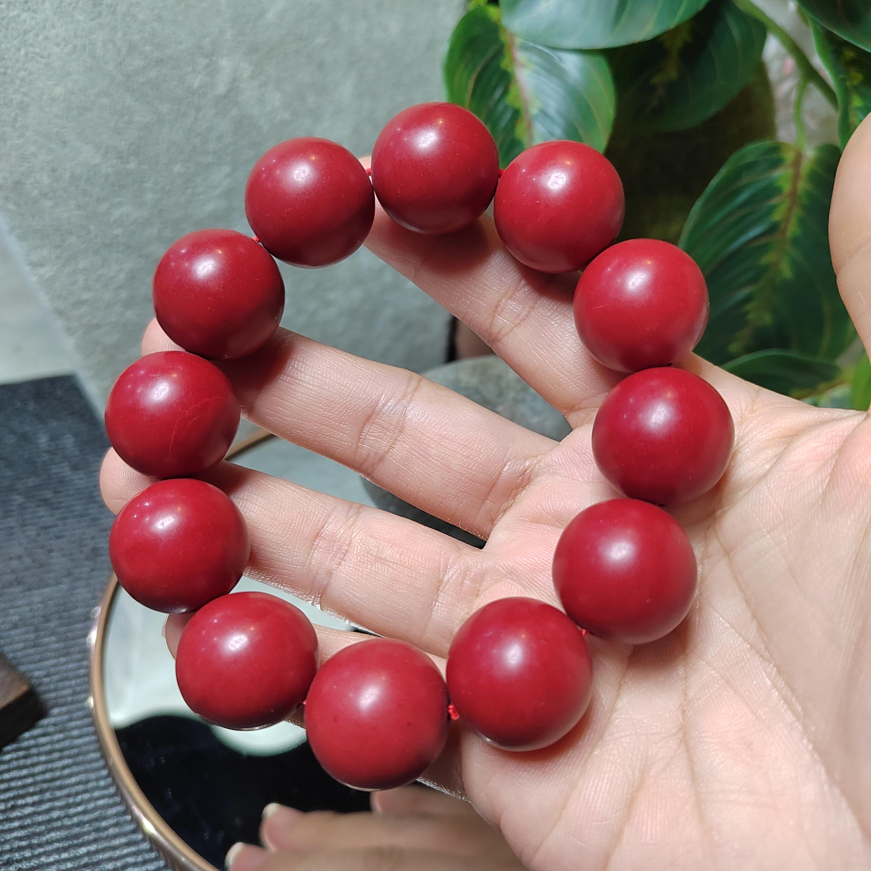 Red beaded bracelet on a hand with a blurred background