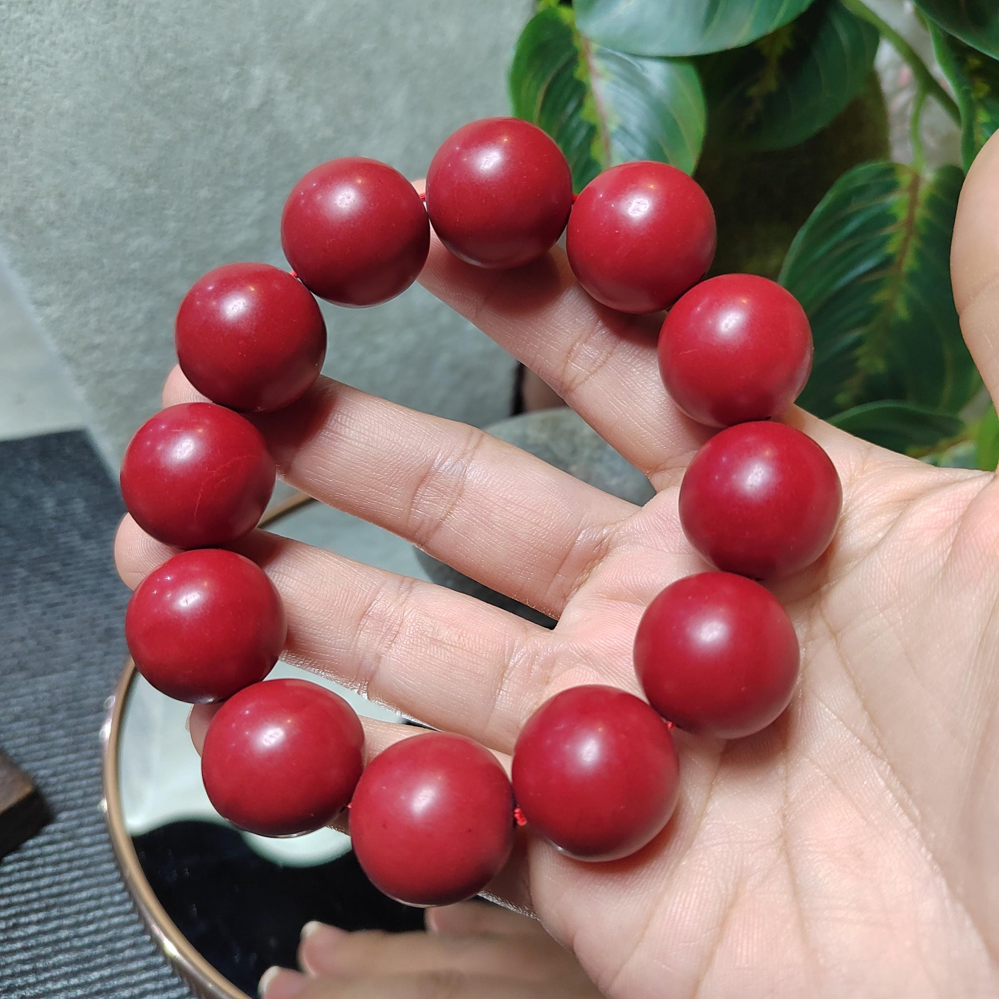 Red beaded bracelet on a hand with a blurred background
