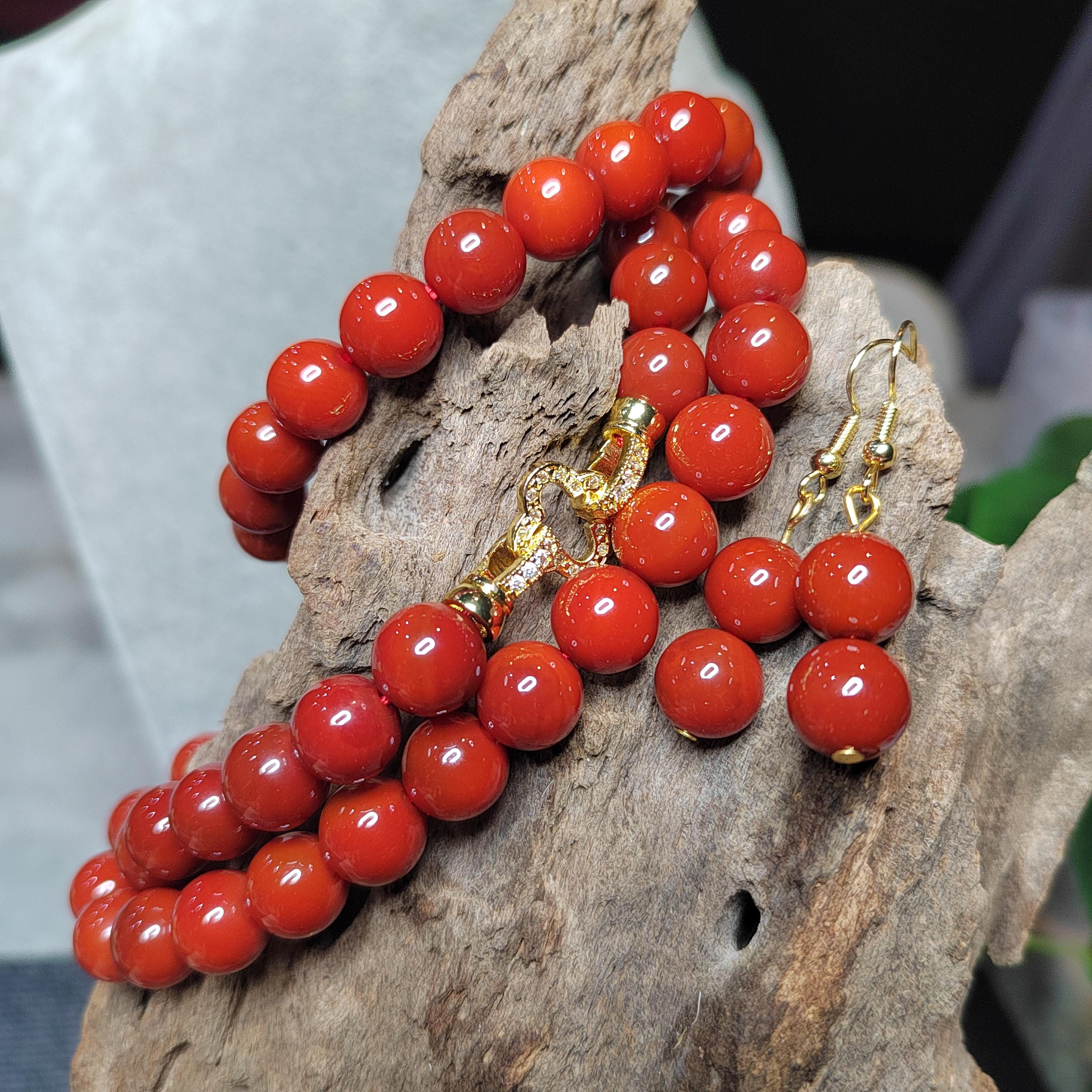 Red beaded bracelet and earrings on a wooden surface