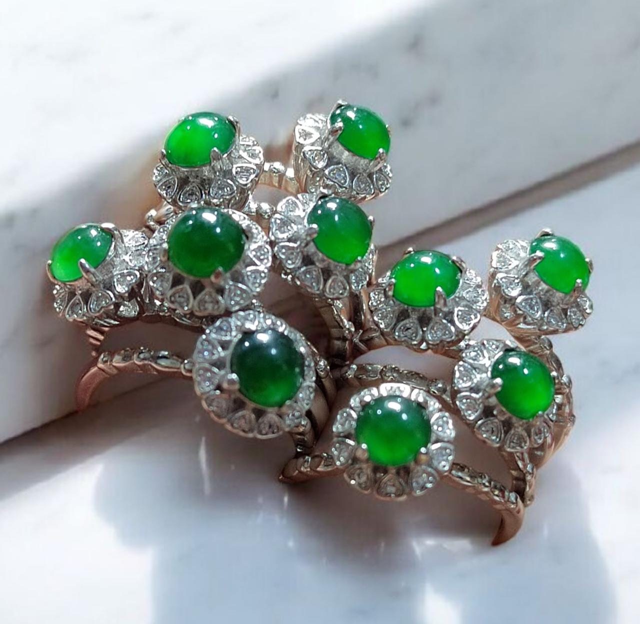 Pair of earrings with green gemstones and diamond-like accents on a white background