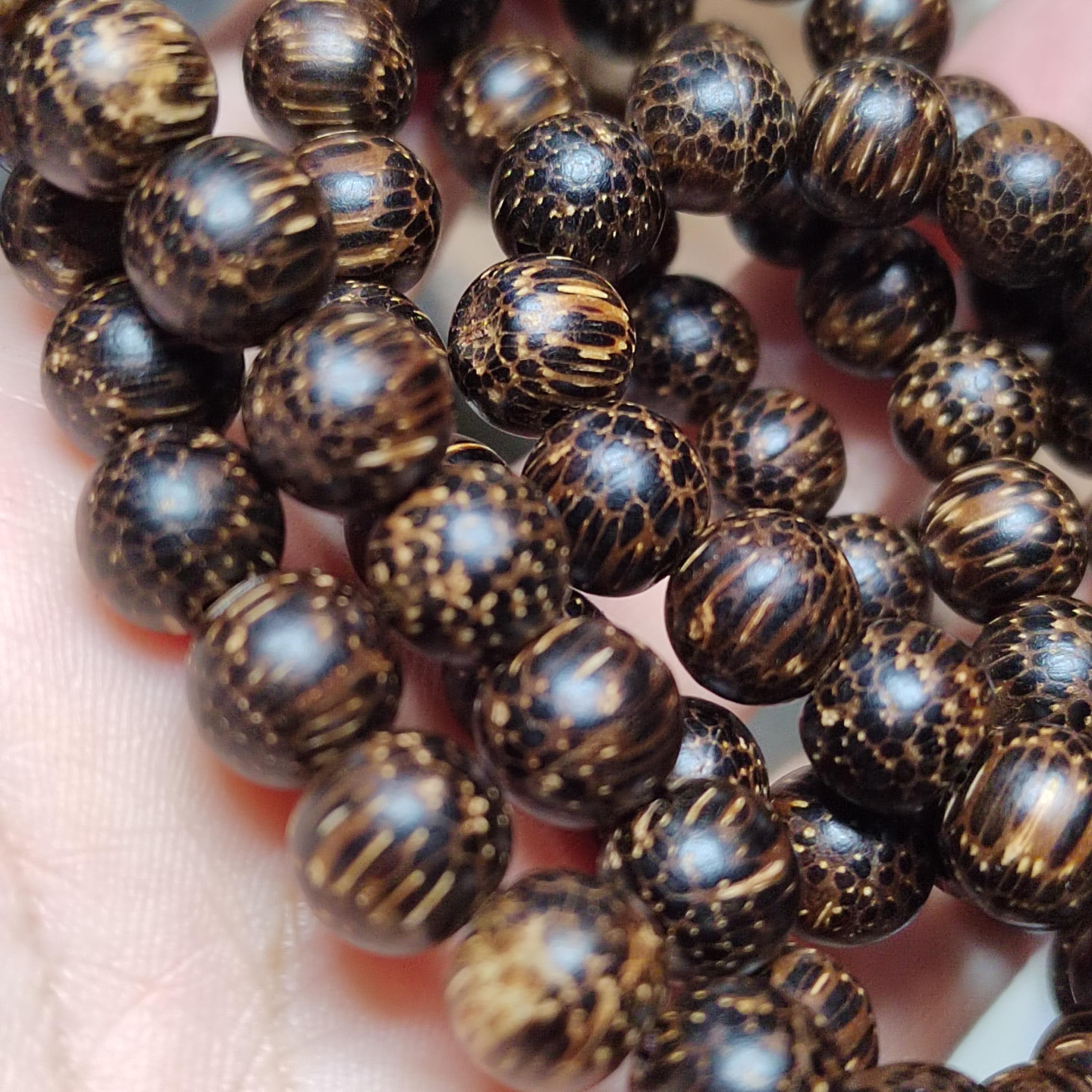 Close-up of dark brown beaded necklace held in hand