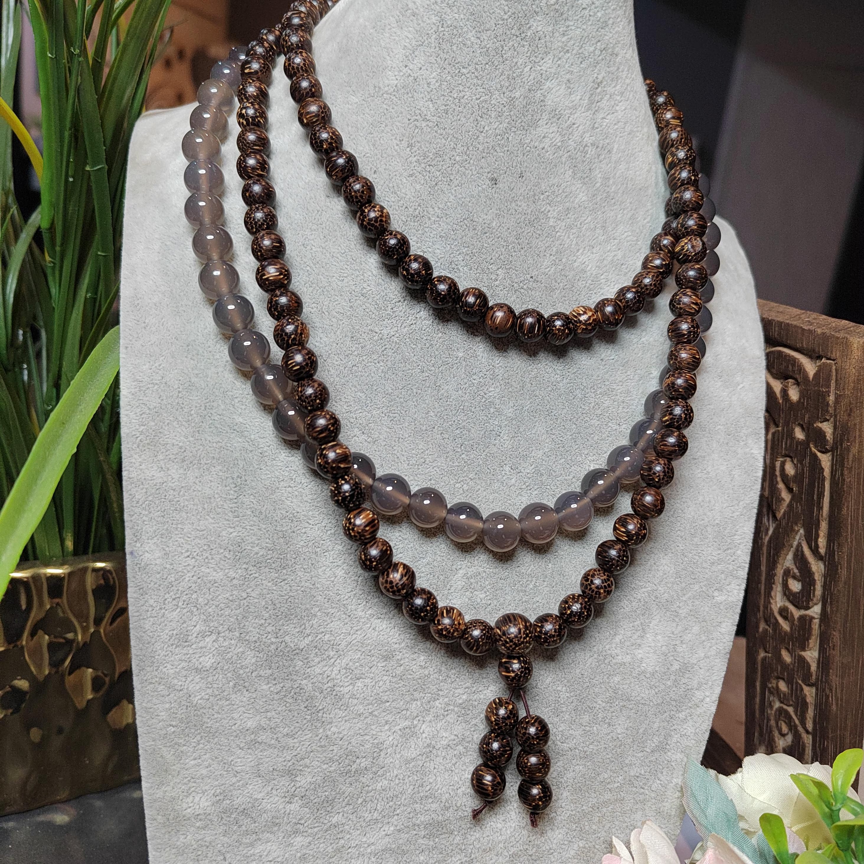 Beaded necklace on a gray stand with a blurred background