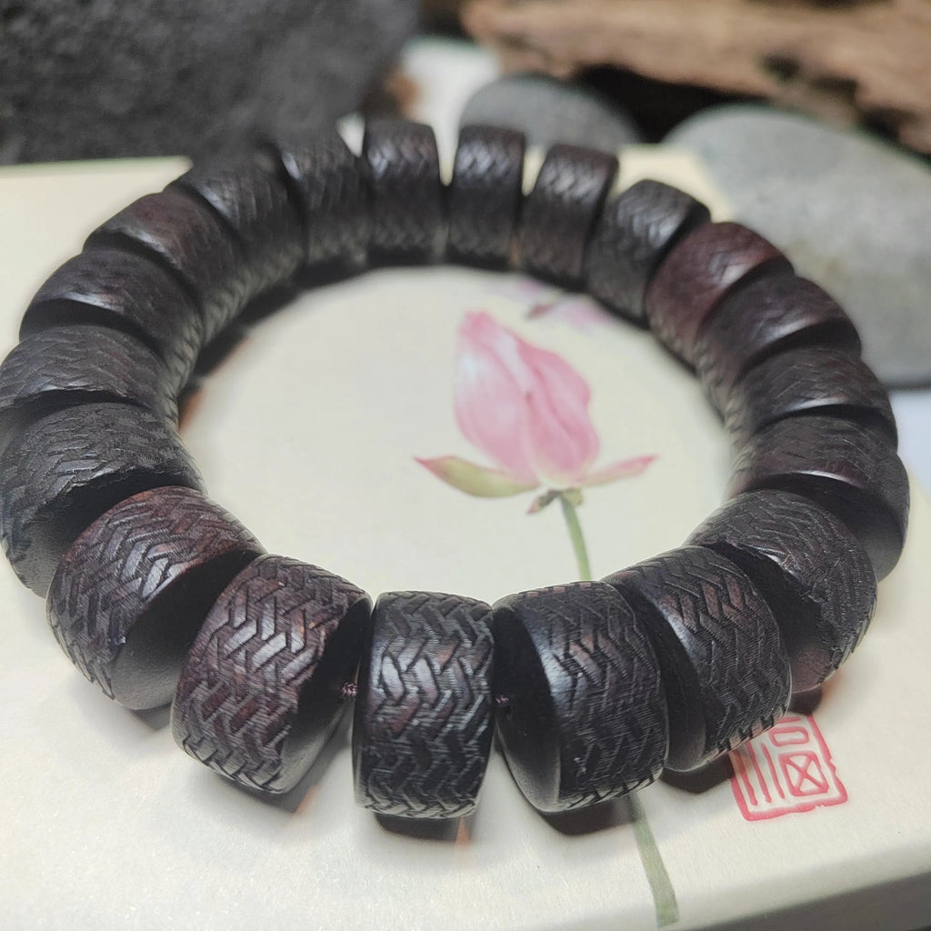 Wooden bracelet with intricate carvings on a ceramic plate with a floral design