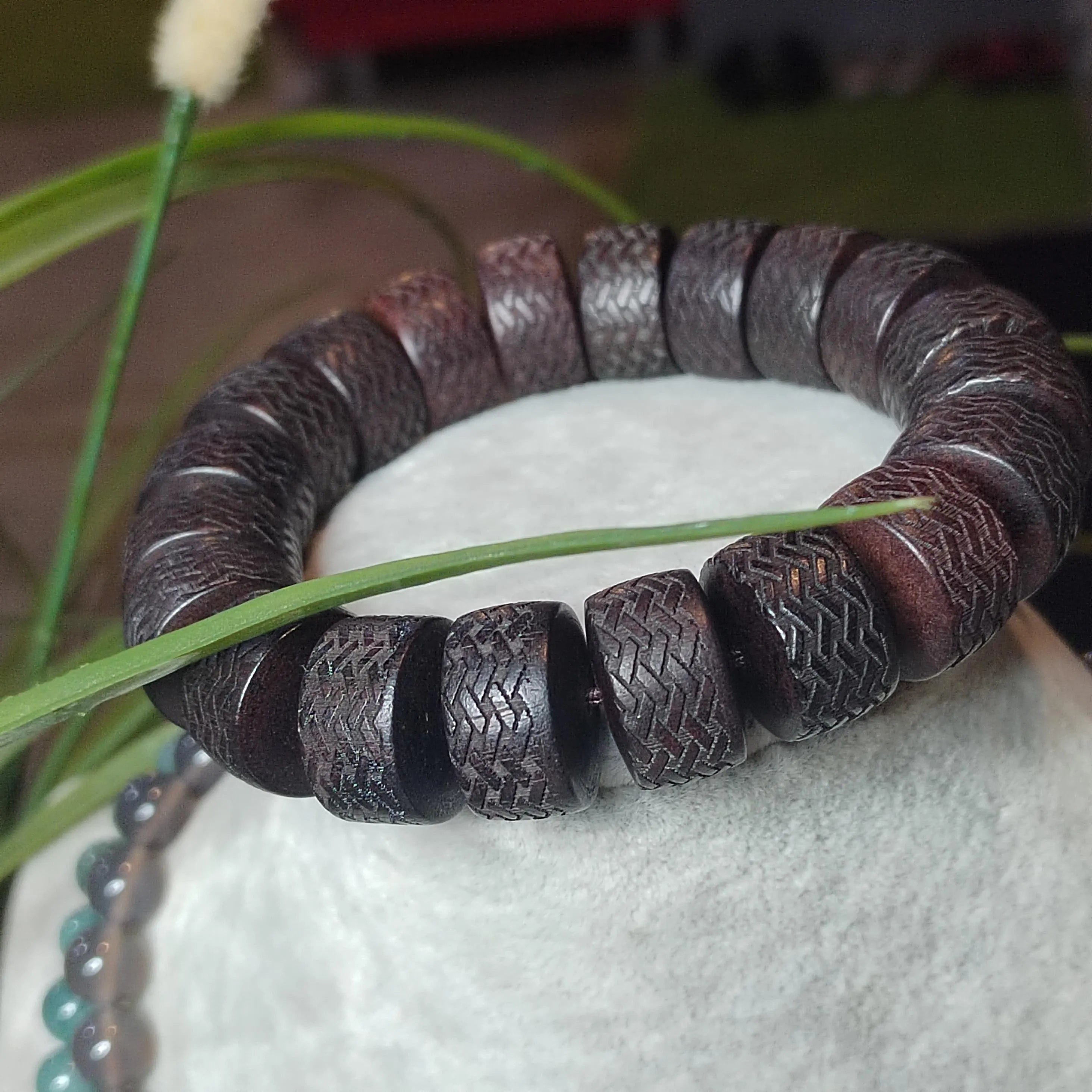 Brown textured bracelet on a white surface with green grass