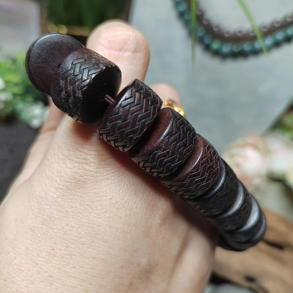 Close-up of a hand holding a dark brown textured bracelet.