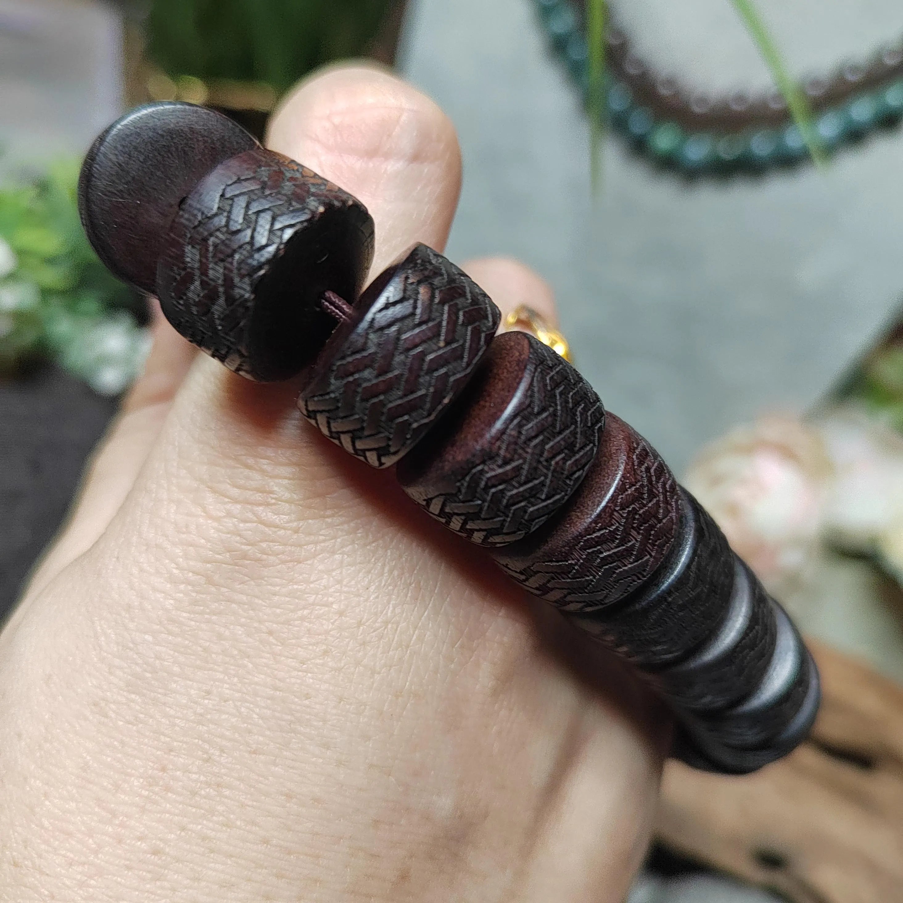 Close-up of a hand holding a dark brown textured bracelet.