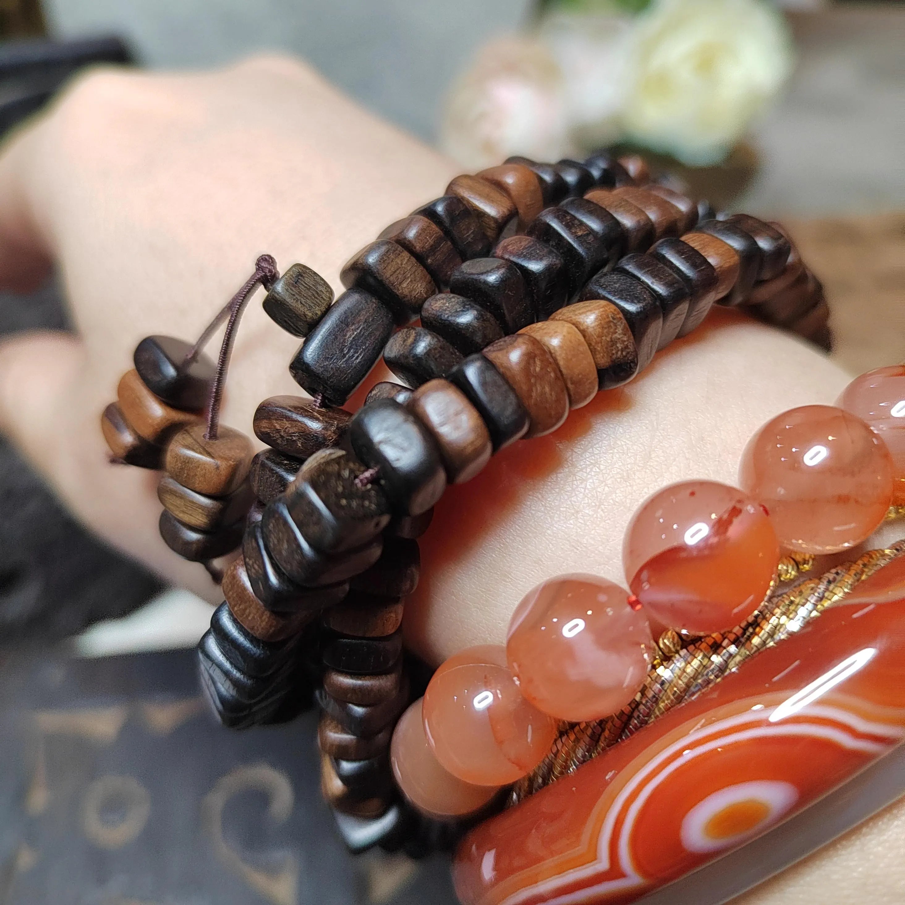Close-up of a hand wearing multiple wooden beaded bracelets on a blurred background