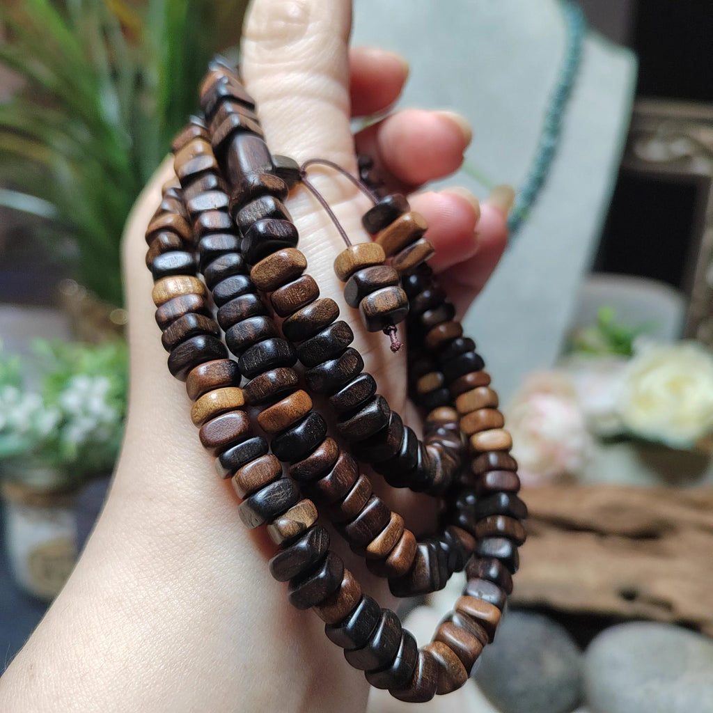 Wooden beaded bracelets held in a hand with a blurred natural background