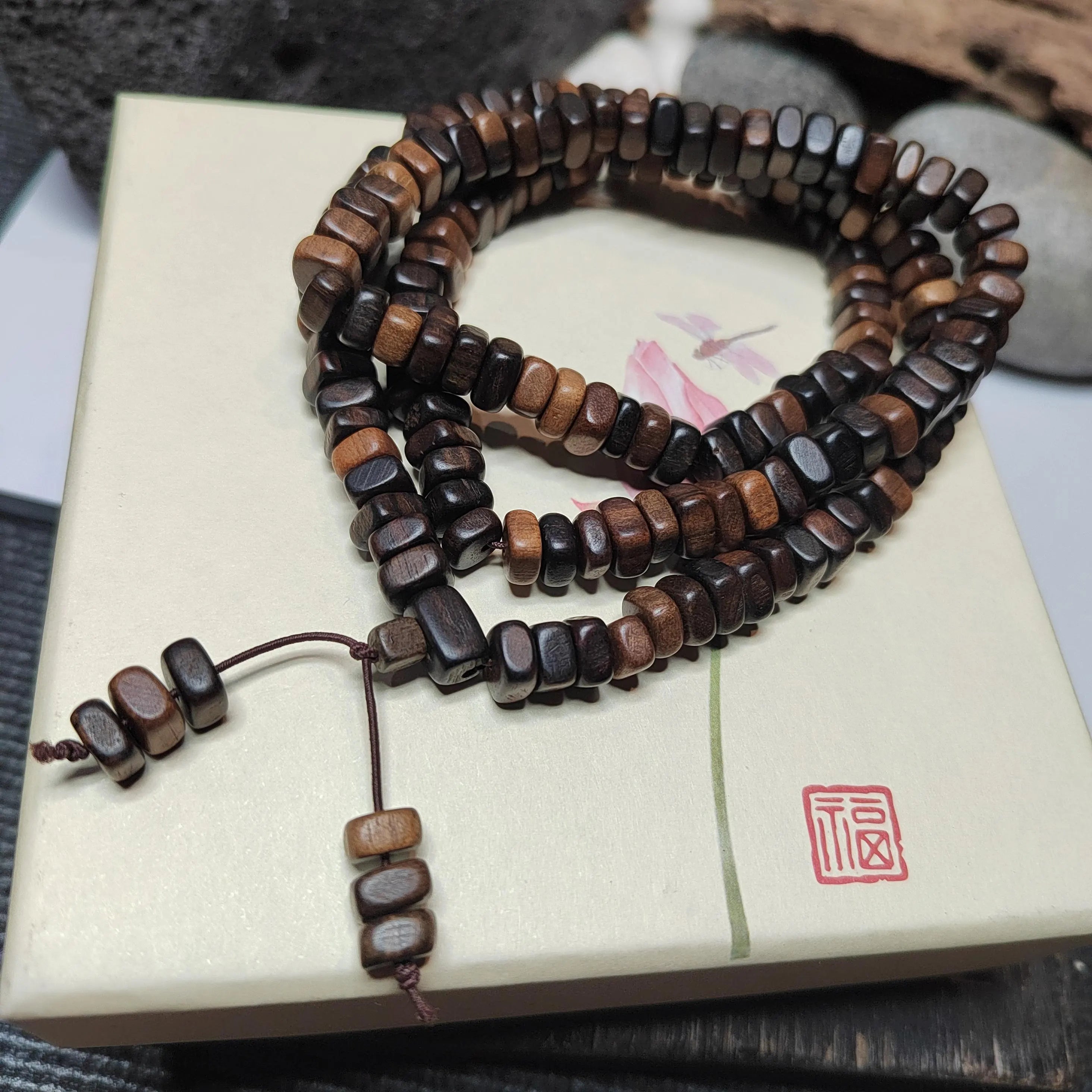 Wooden beaded bracelet on a decorative box with a red stamp