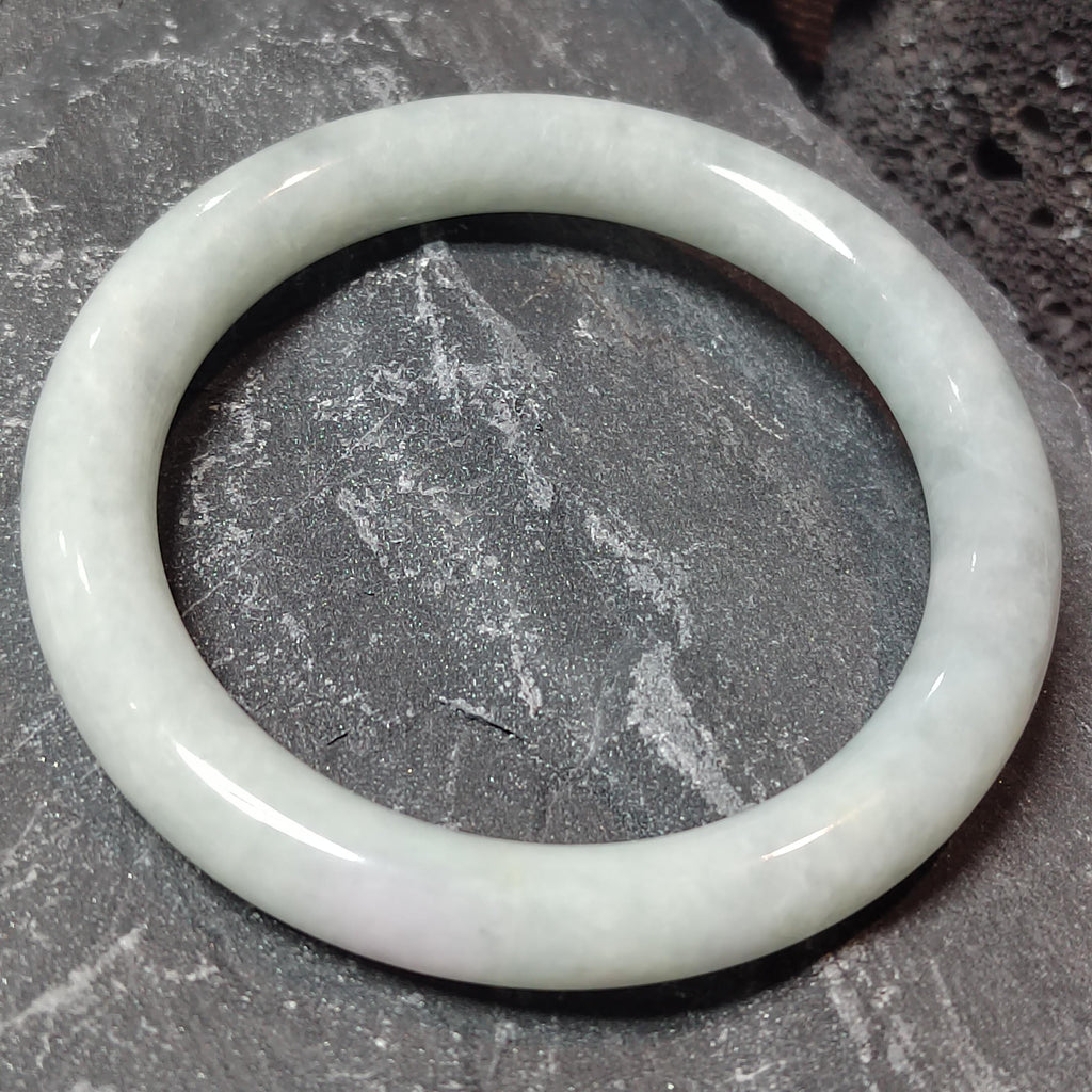White jade bracelet on a textured gray surface