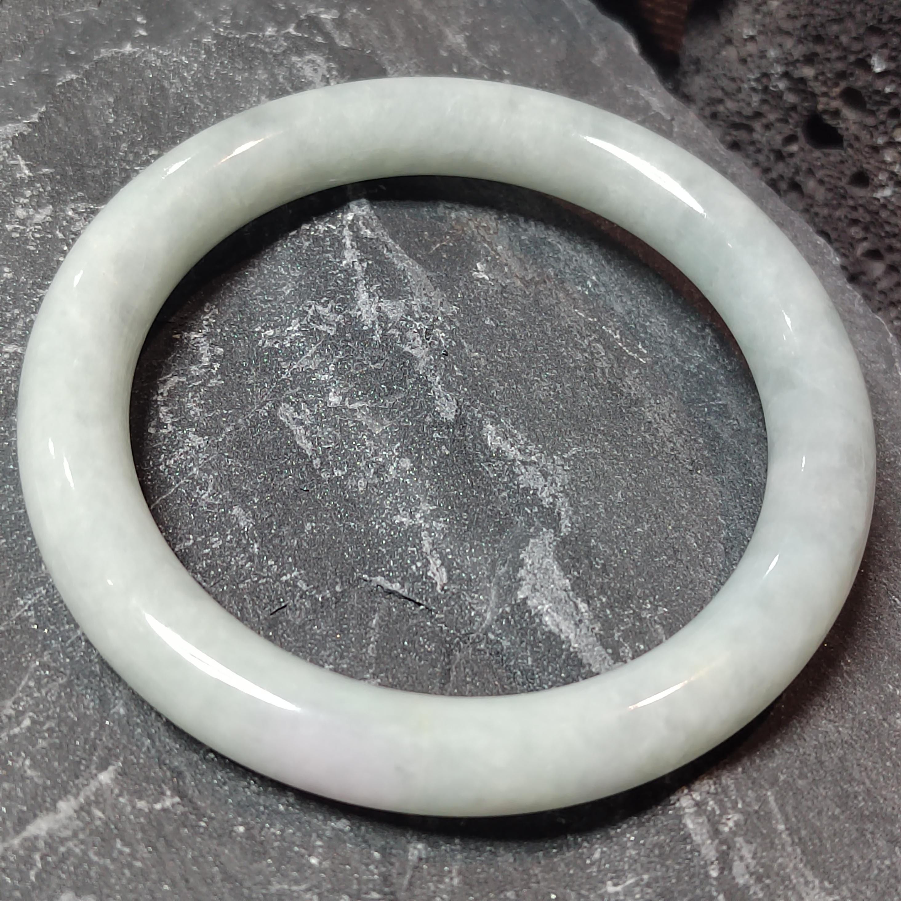White jade bracelet on a textured gray surface
