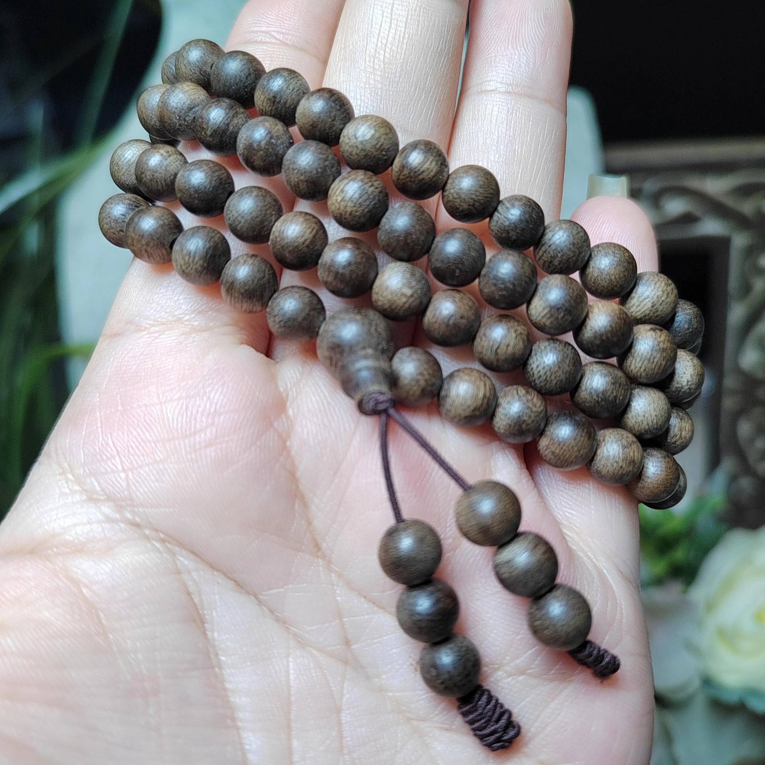 Wooden prayer beads held in a hand with a blurred background