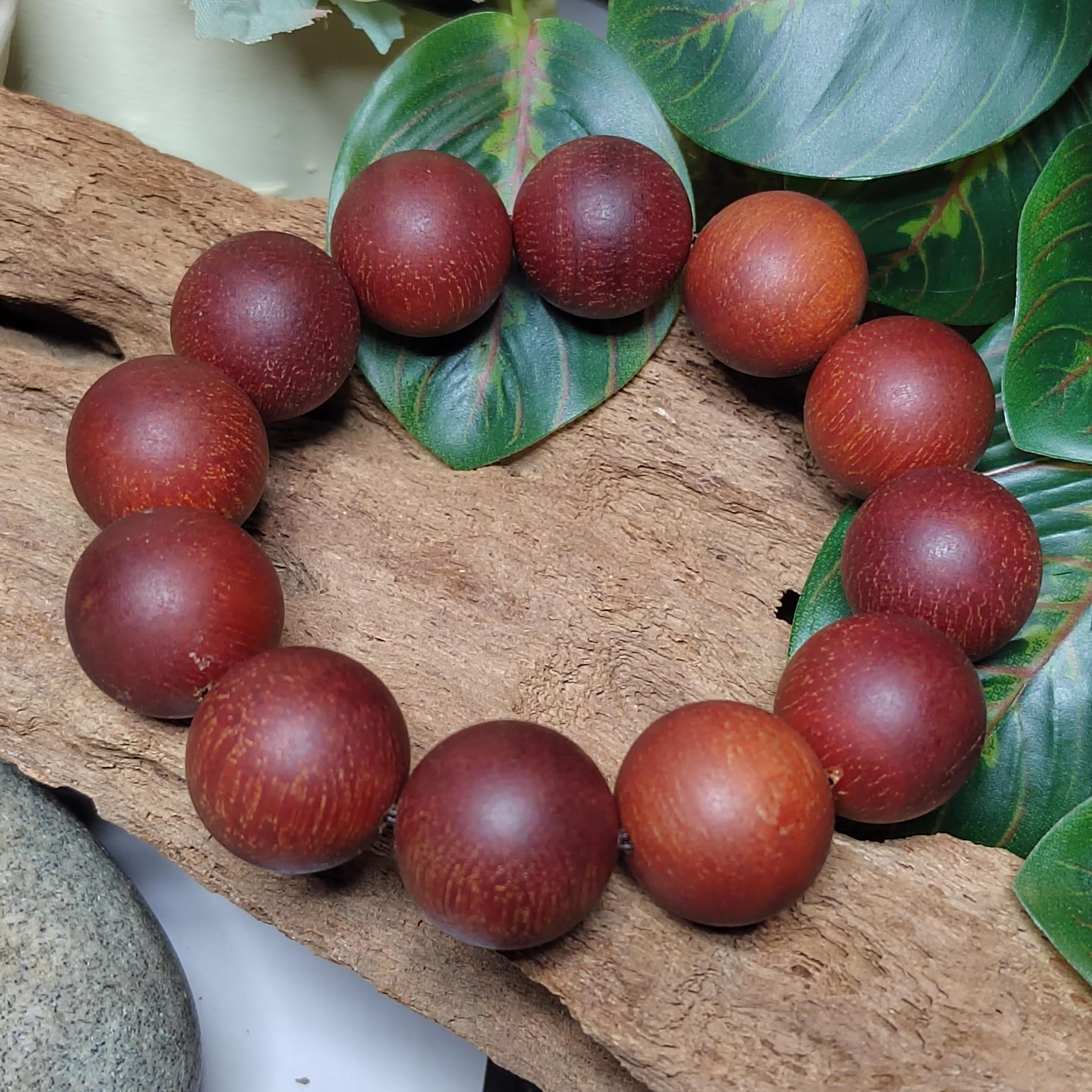 Wooden bead bracelet on a natural wooden surface with leaves in the background