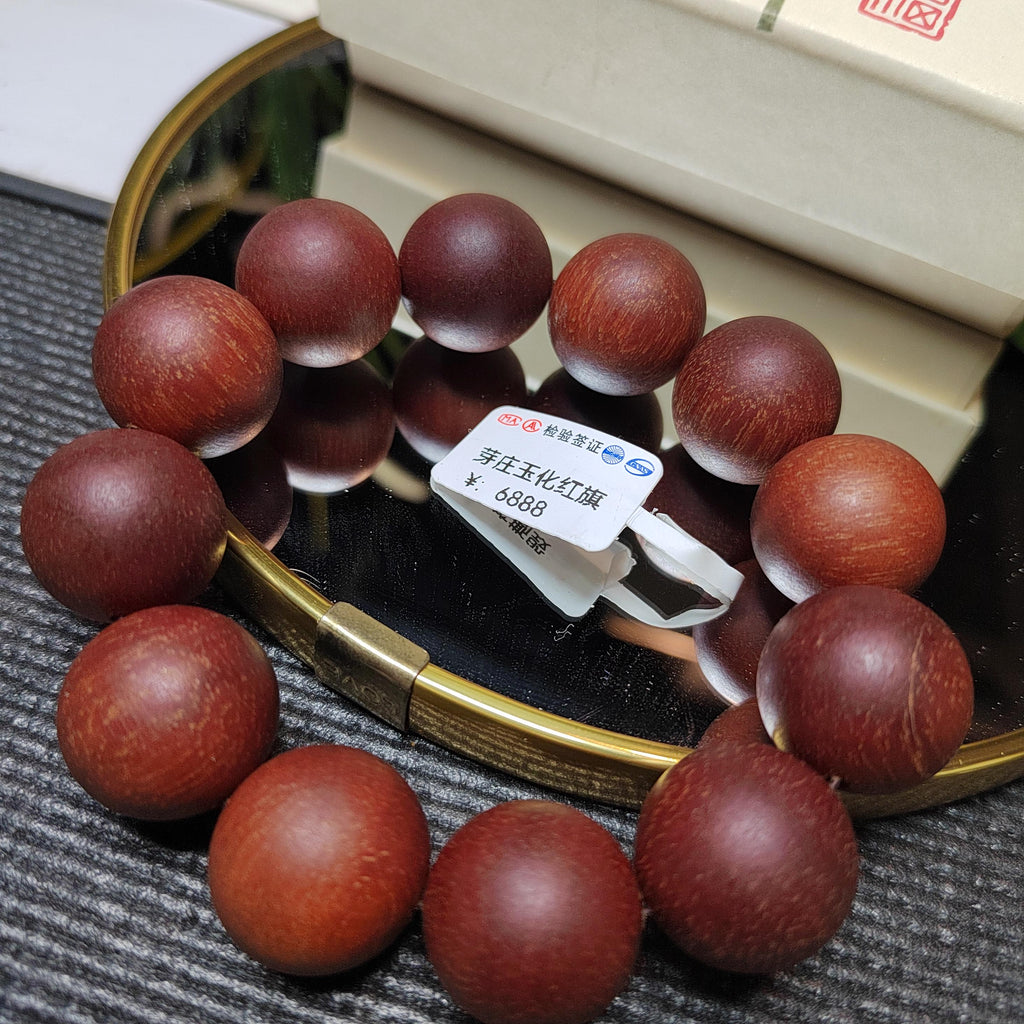 Wooden beaded bracelet on a reflective surface with a label