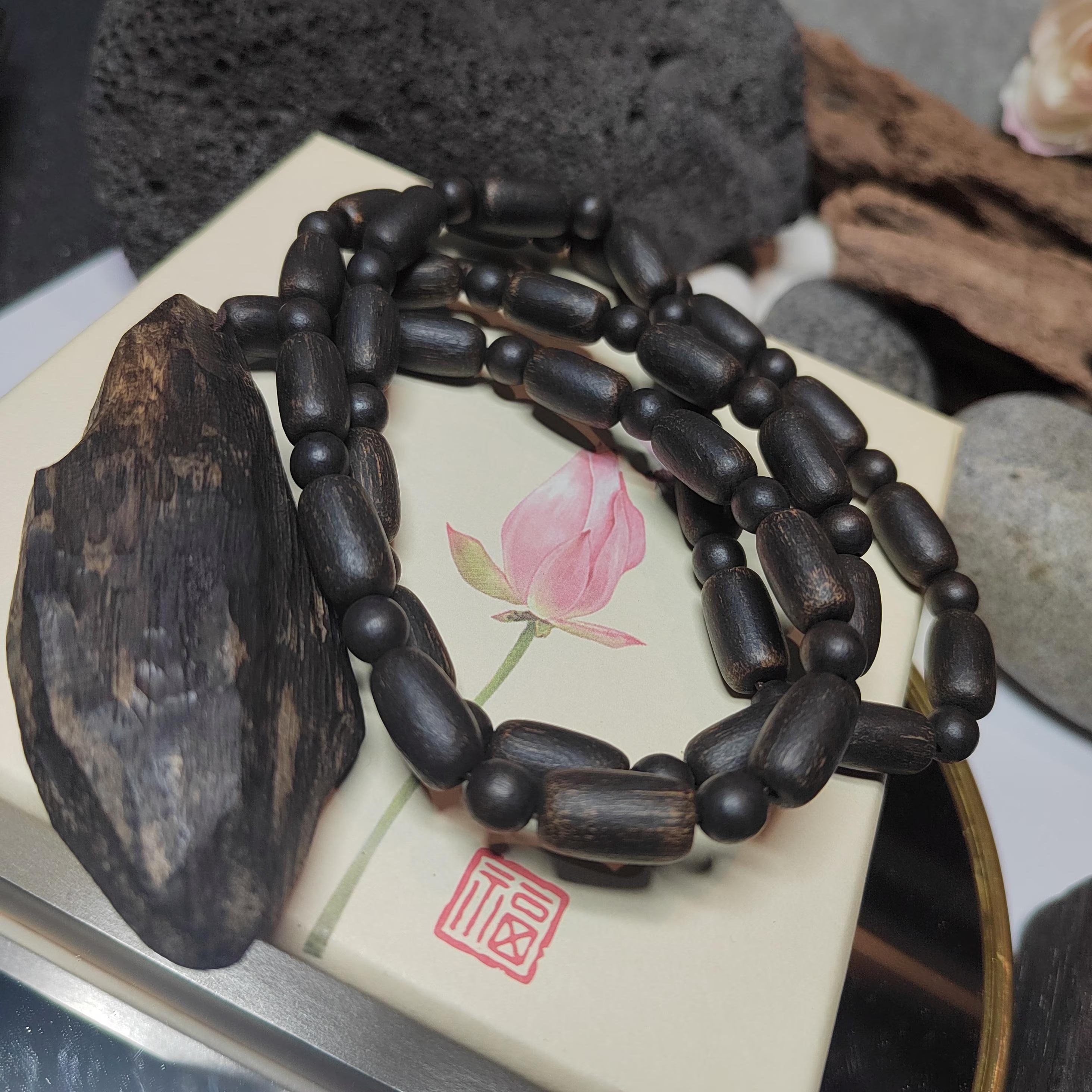 Dark wooden beaded bracelet on a decorative stone with floral design