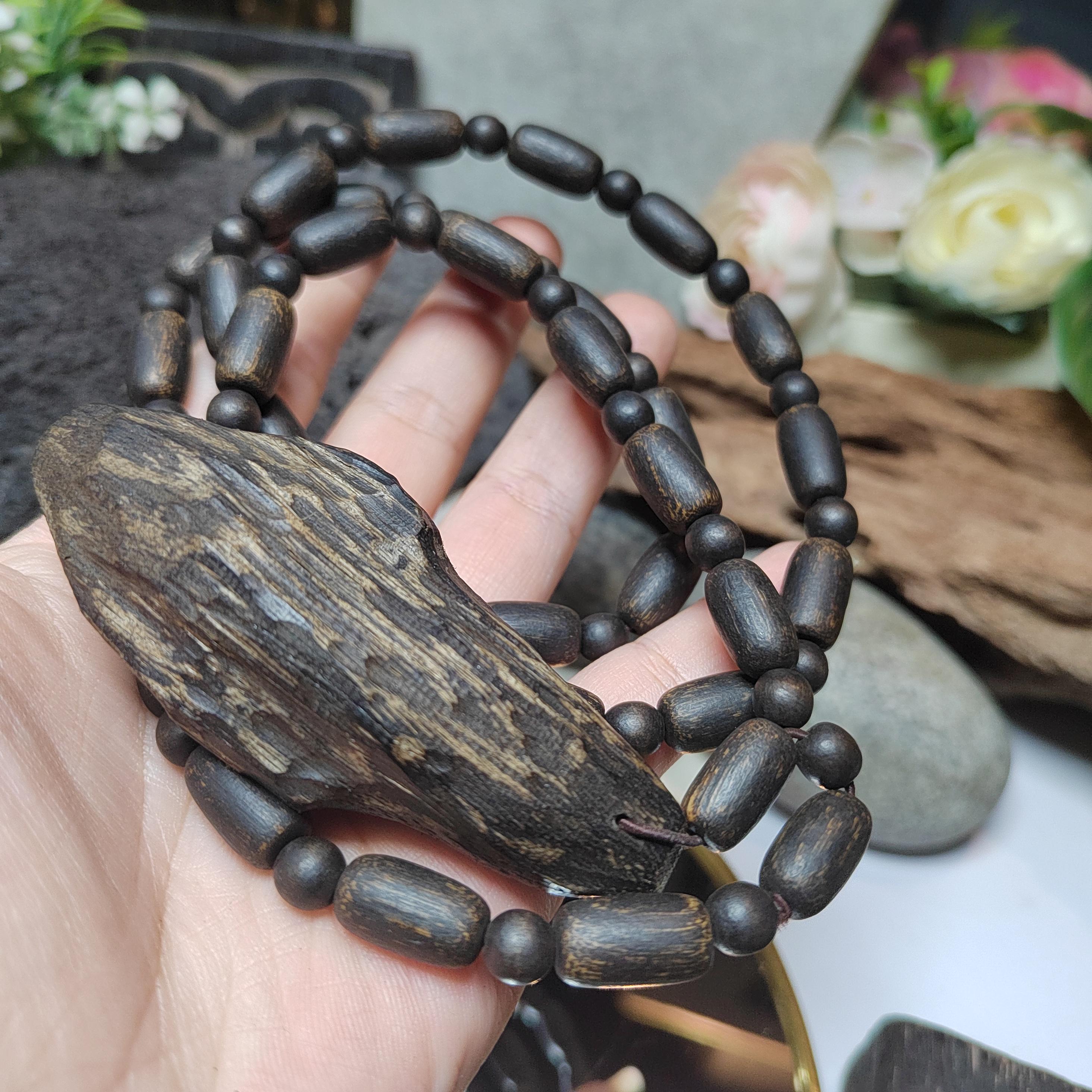 Wooden bracelet with a large leaf-shaped piece held in a hand against a blurred natural background.