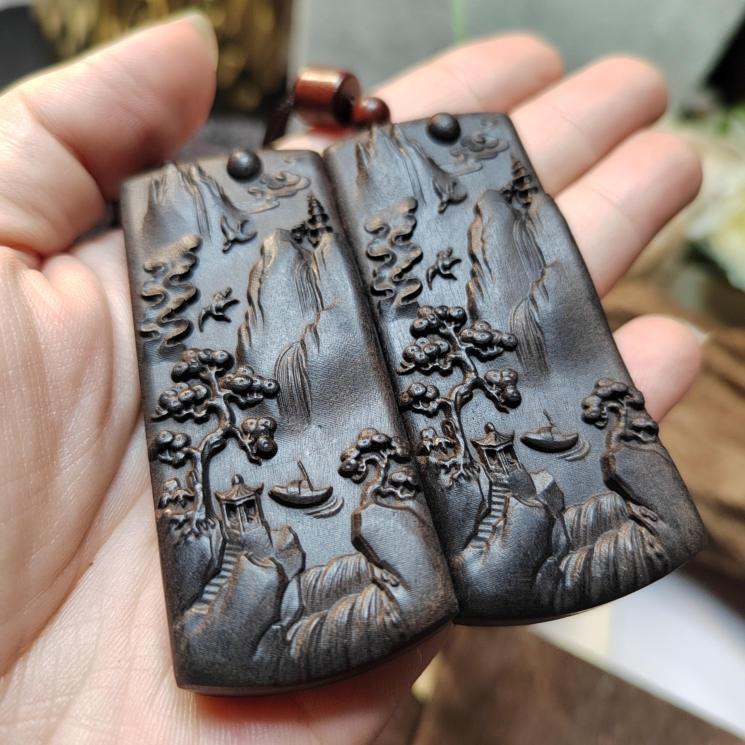 Two intricately carved wooden plaques held in a hand with a blurred background