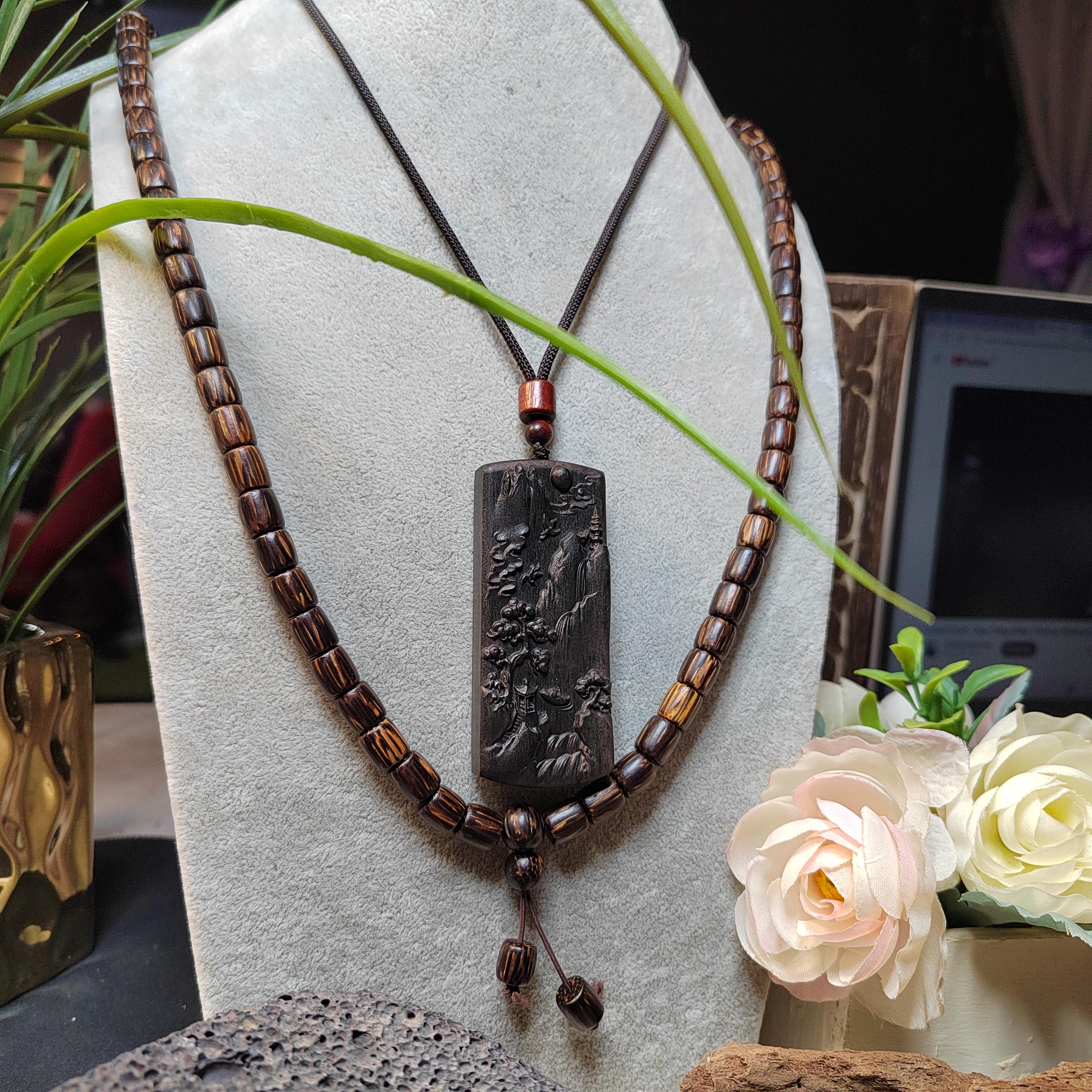 Necklace with a pendant on a white stand with flowers and decor in the background