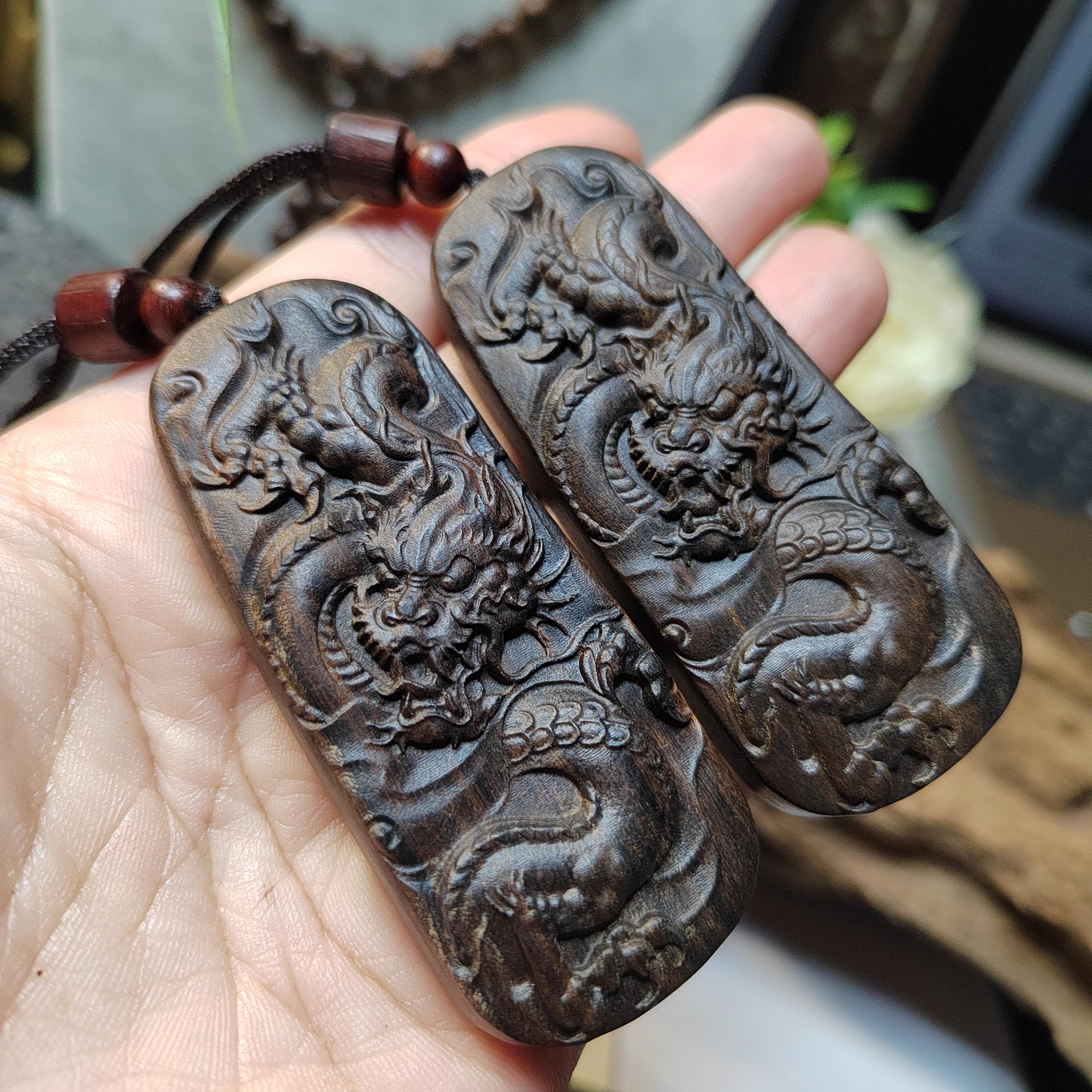 Two dragon-shaped carvings on a hand with a blurred background