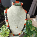 Necklace with colorful beads on a mannequin bust with green leaves in the foreground