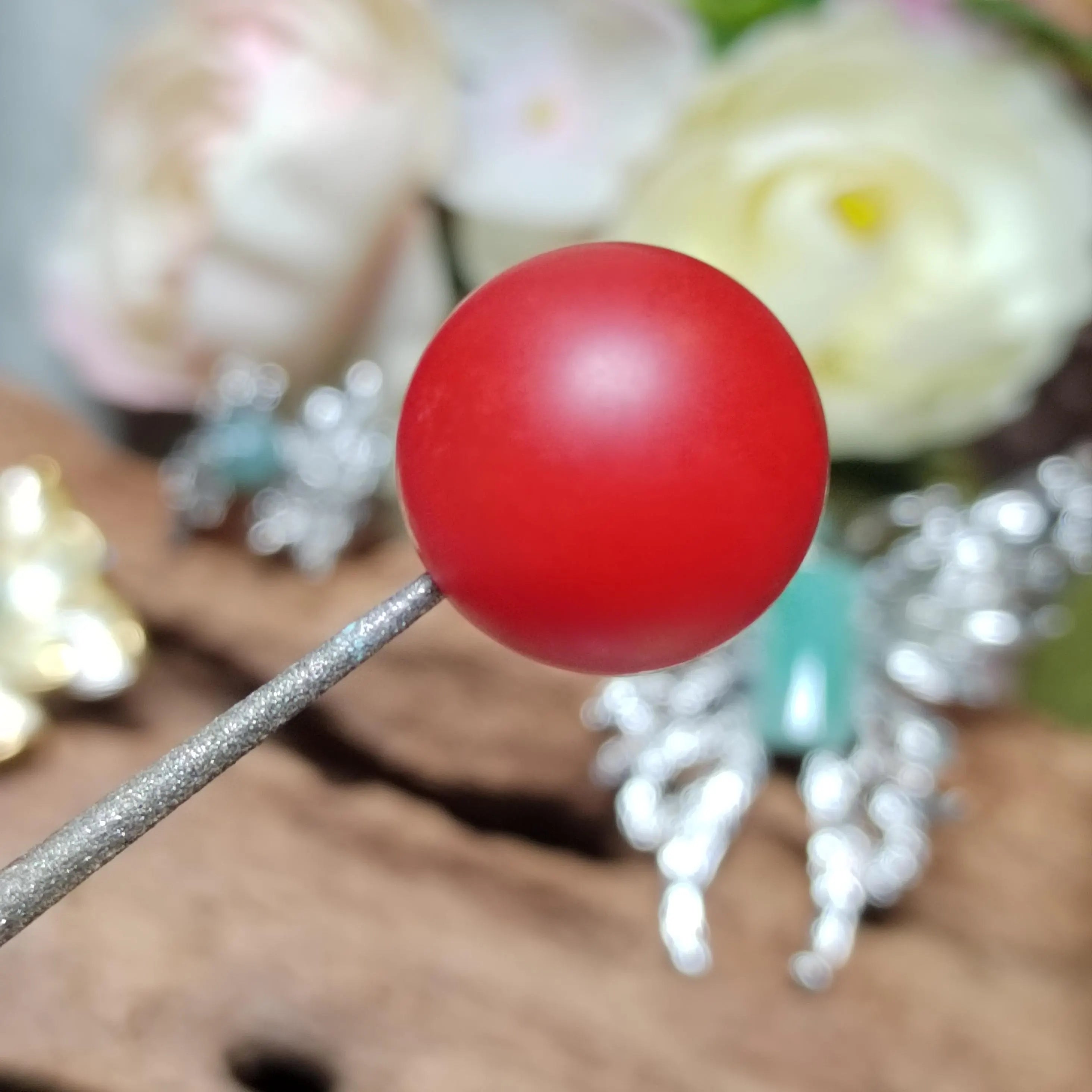 Red Nanhong bead on a stick with blurred floral background