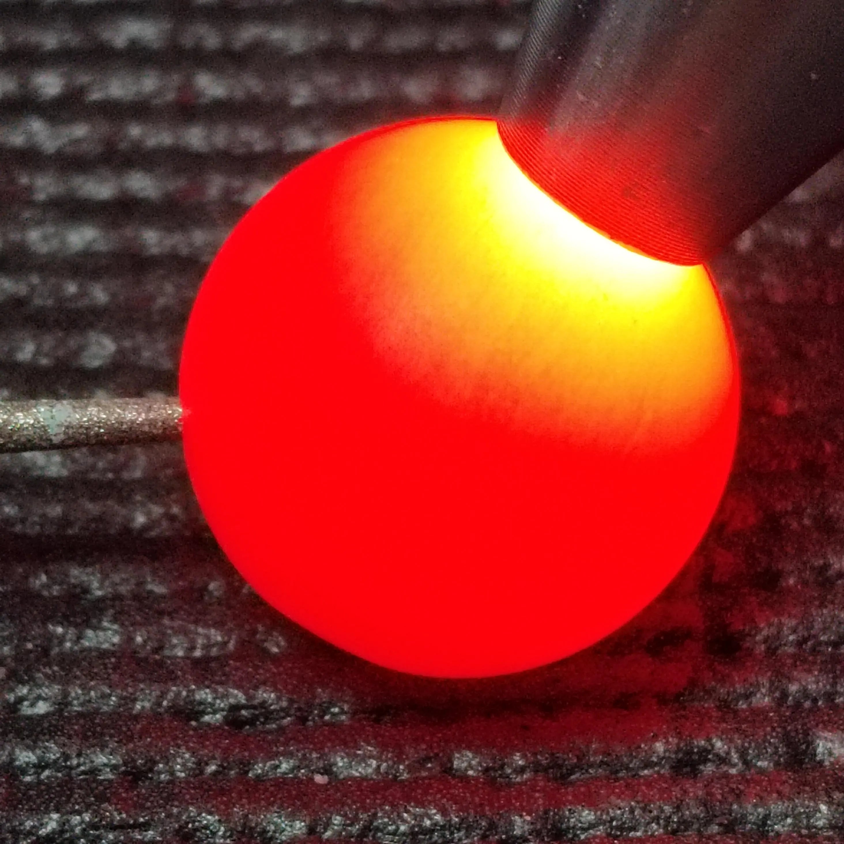 Close-up of a red glowing Nanhong bead on a textured surface