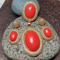 Gold and red earrings on a stone surface