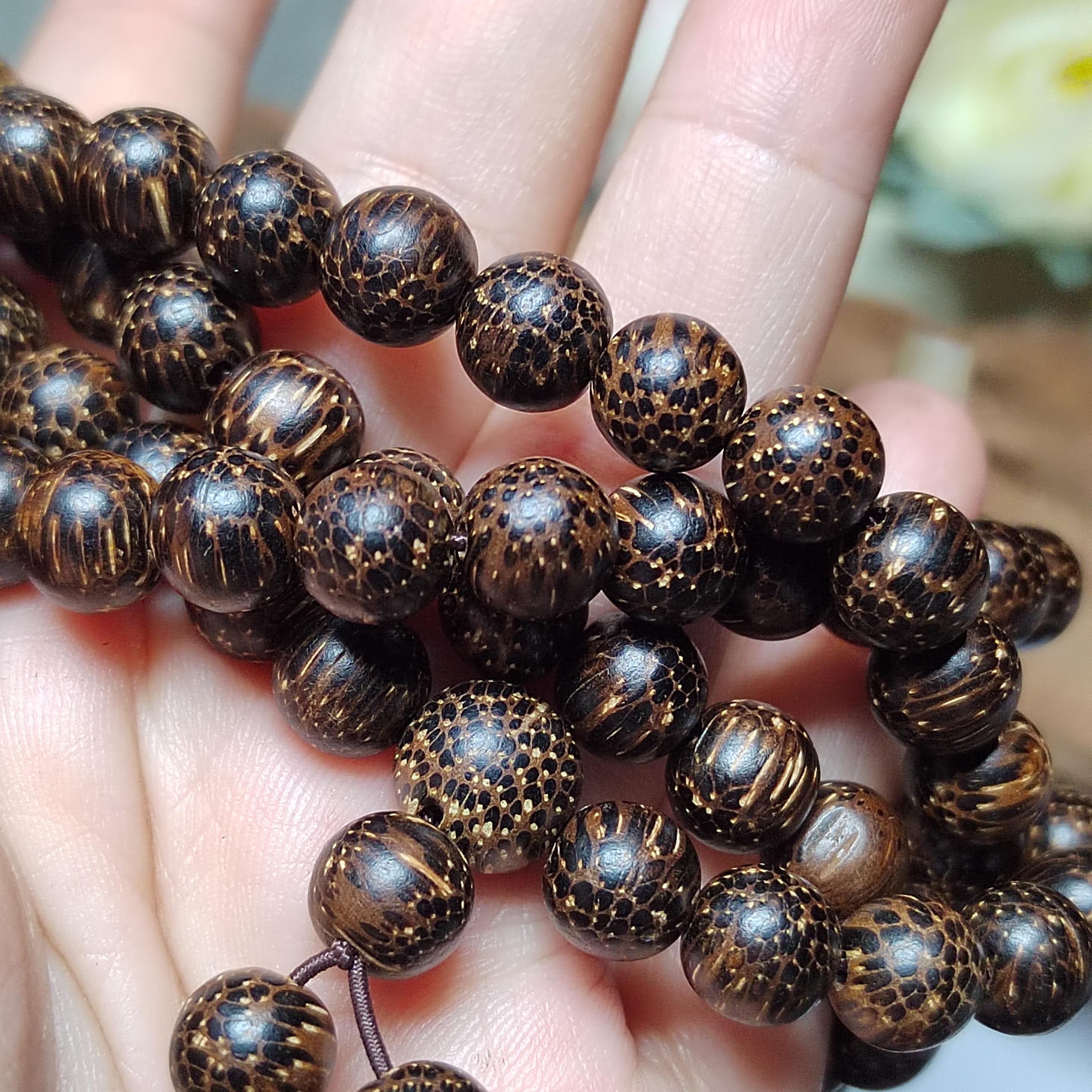 Close-up of a hand holding a string of brown beaded bracelets.