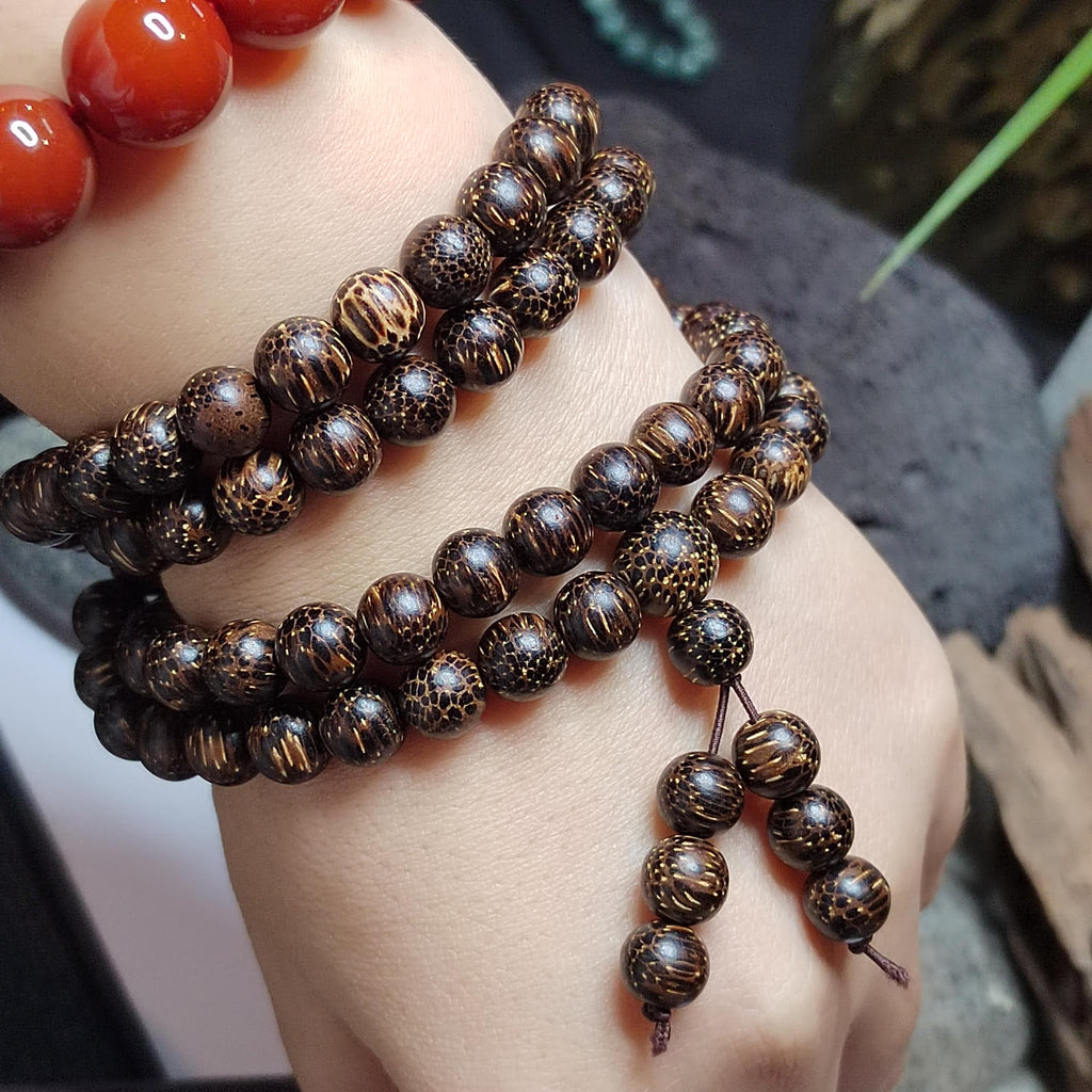 Close-up of a person's wrist wearing multiple brown beaded bracelets.