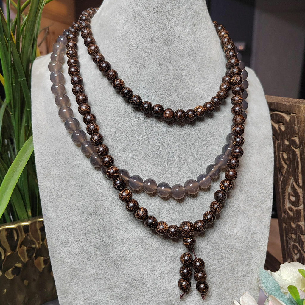 Necklace with brown and clear beads on a gray stand with decorative elements.